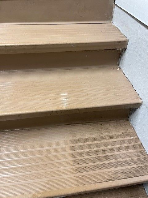A close up of a wooden staircase with a white wall in the background.