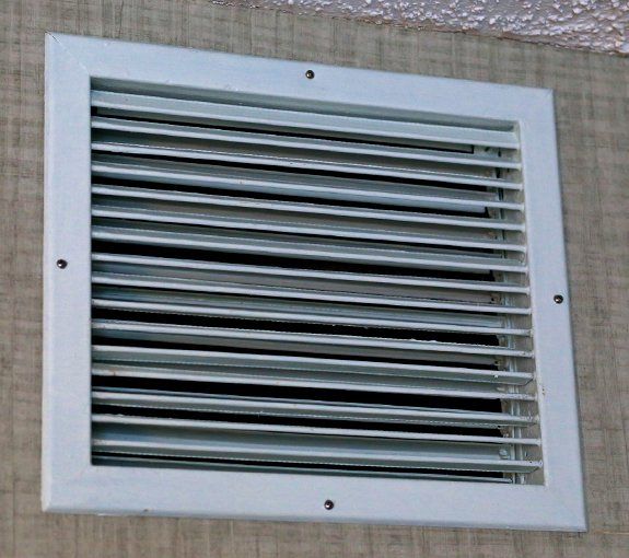 White rectangular air vent on a beige wall.