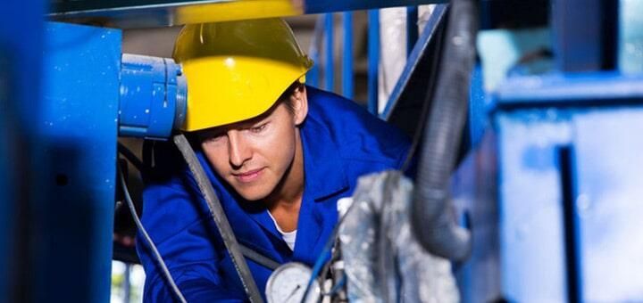 Un hombre que lleva casco y mono azul está trabajando en una máquina.