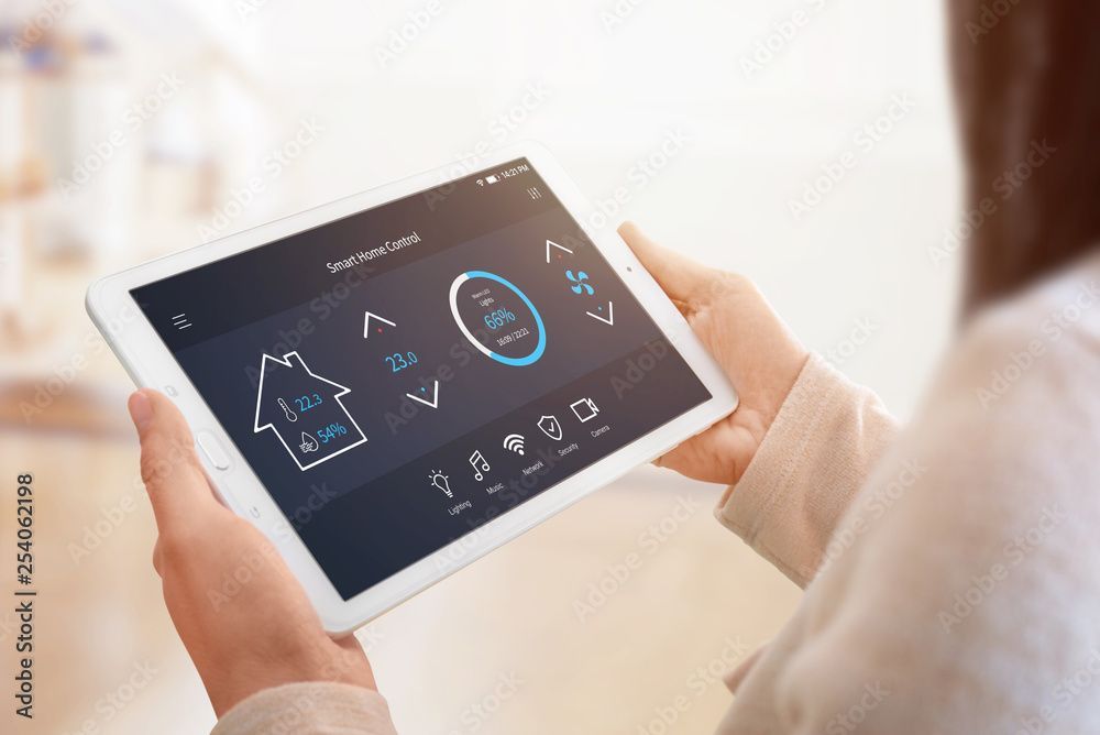 Hand inserting a white outlet cover into an electrical outlet. Beige wall.