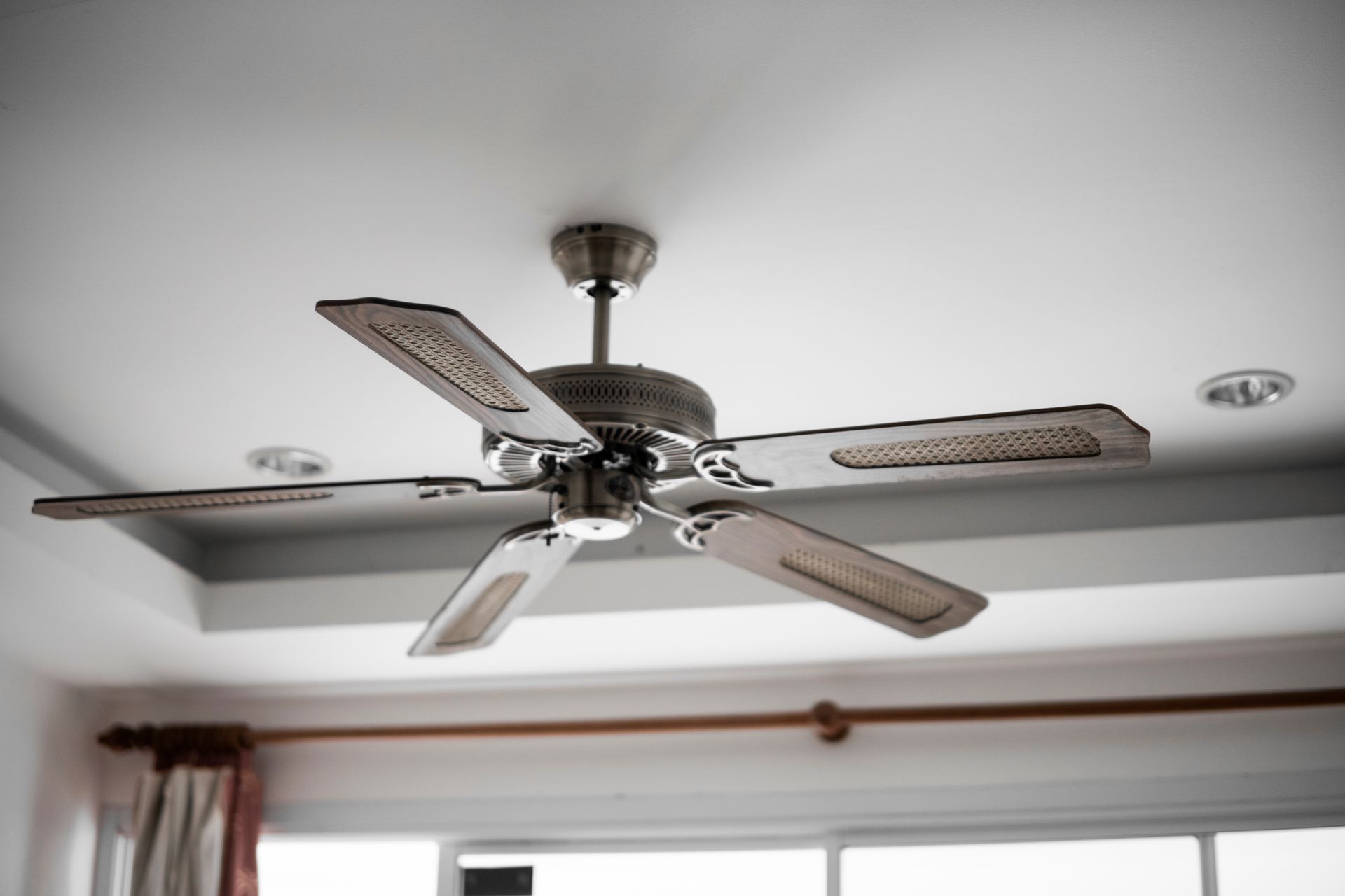 Ceiling fan with five blades, silver color, mounted on a white ceiling.