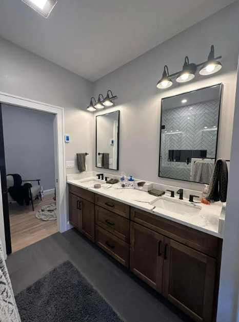Bathroom with double vanity, dark wood cabinets, light gray walls, rectangular mirrors, and black fixtures.