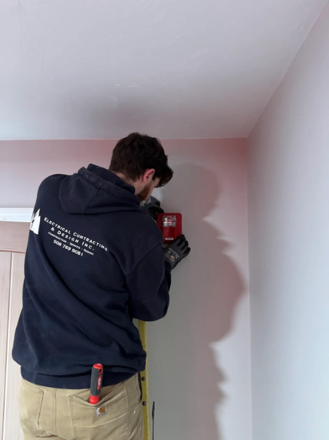 White GFCI electrical outlet with red reset button on a textured wall.