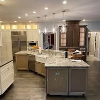Hands testing electrical wiring in a panel, wearing gloves; wires are yellow, orange, and blue.