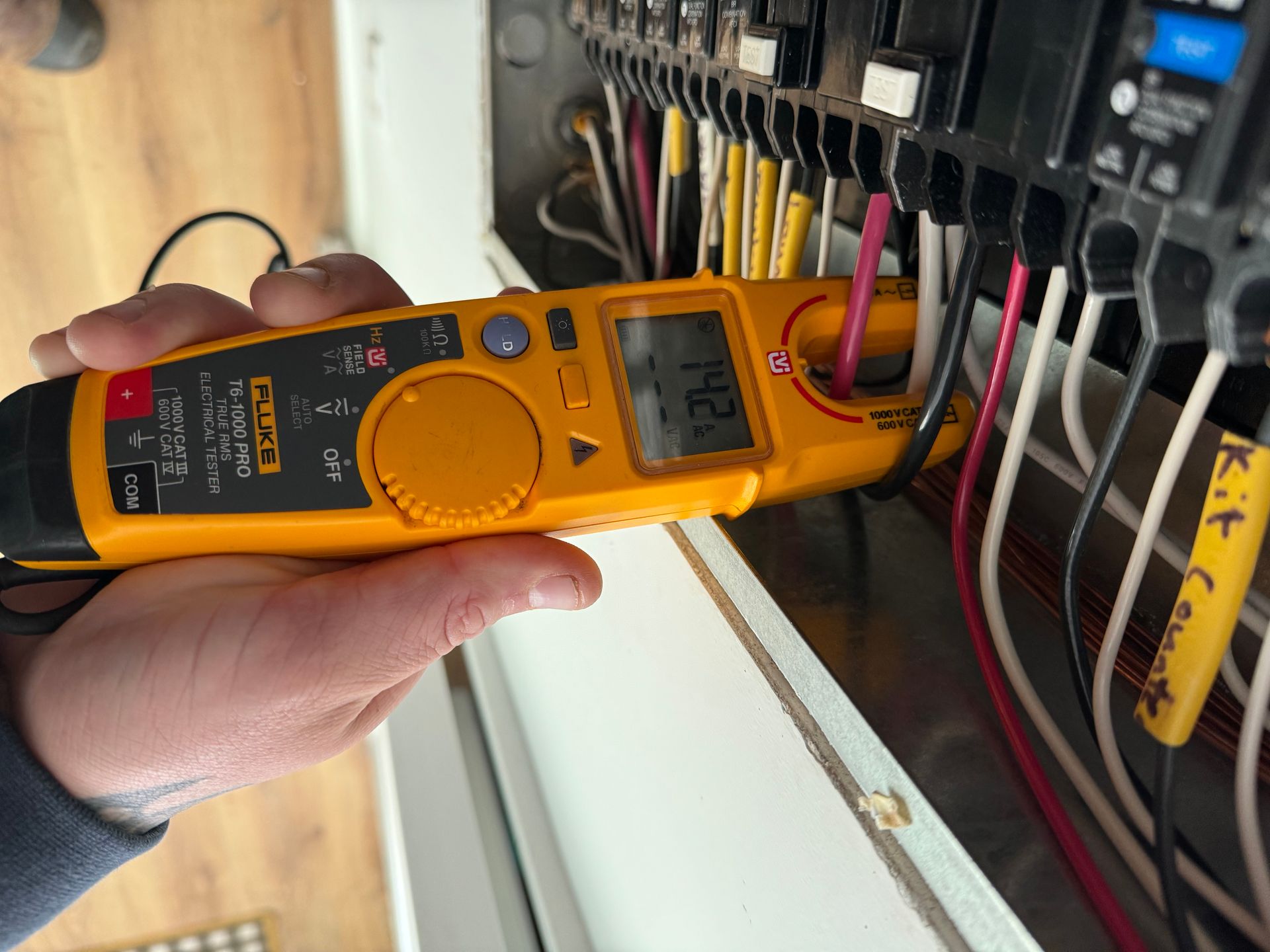 Hand inserting a white outlet cover into an electrical outlet. Beige wall.
