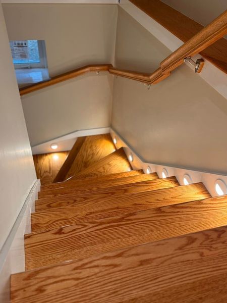 Dark gray outdoor wall-mounted light fixture illuminating a textured tan wall.