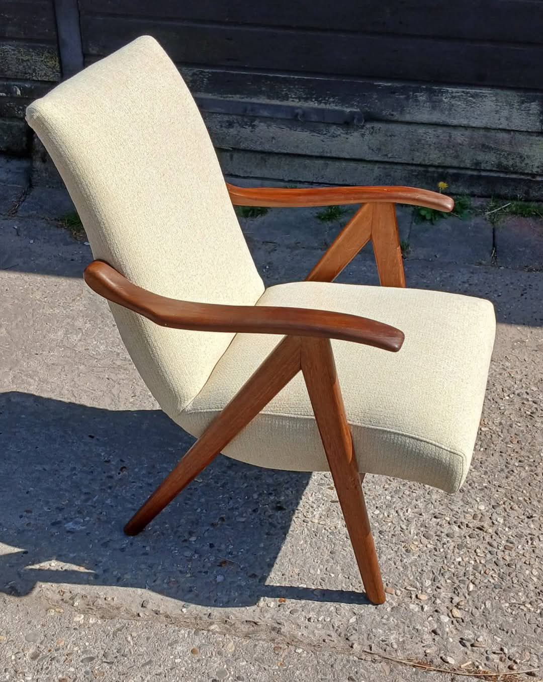 Crèmekleurige, beklede fauteuil in mid-century modern-stijl met houten frame en armleuningen, buiten op beton.