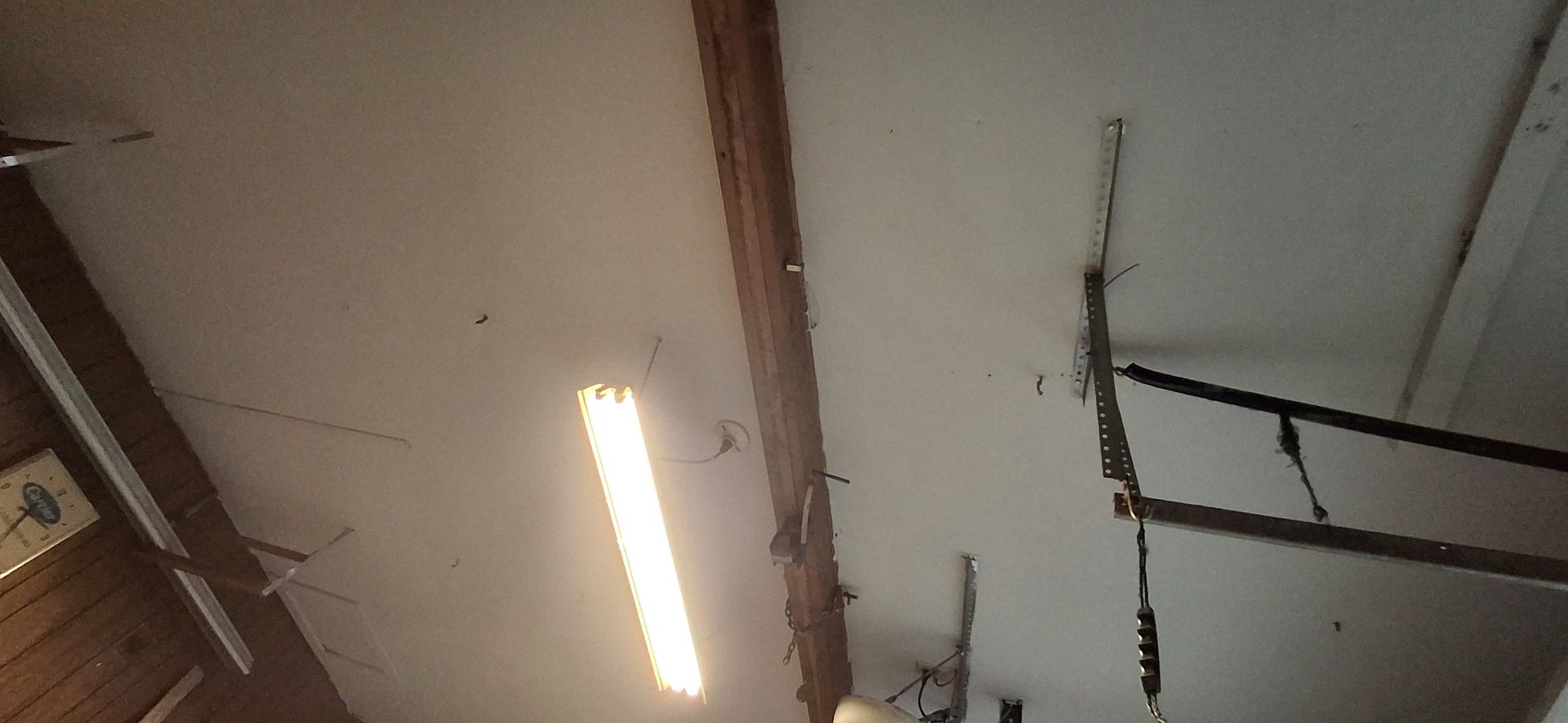 Ceiling with a long light, wooden beam, and ladder structure.