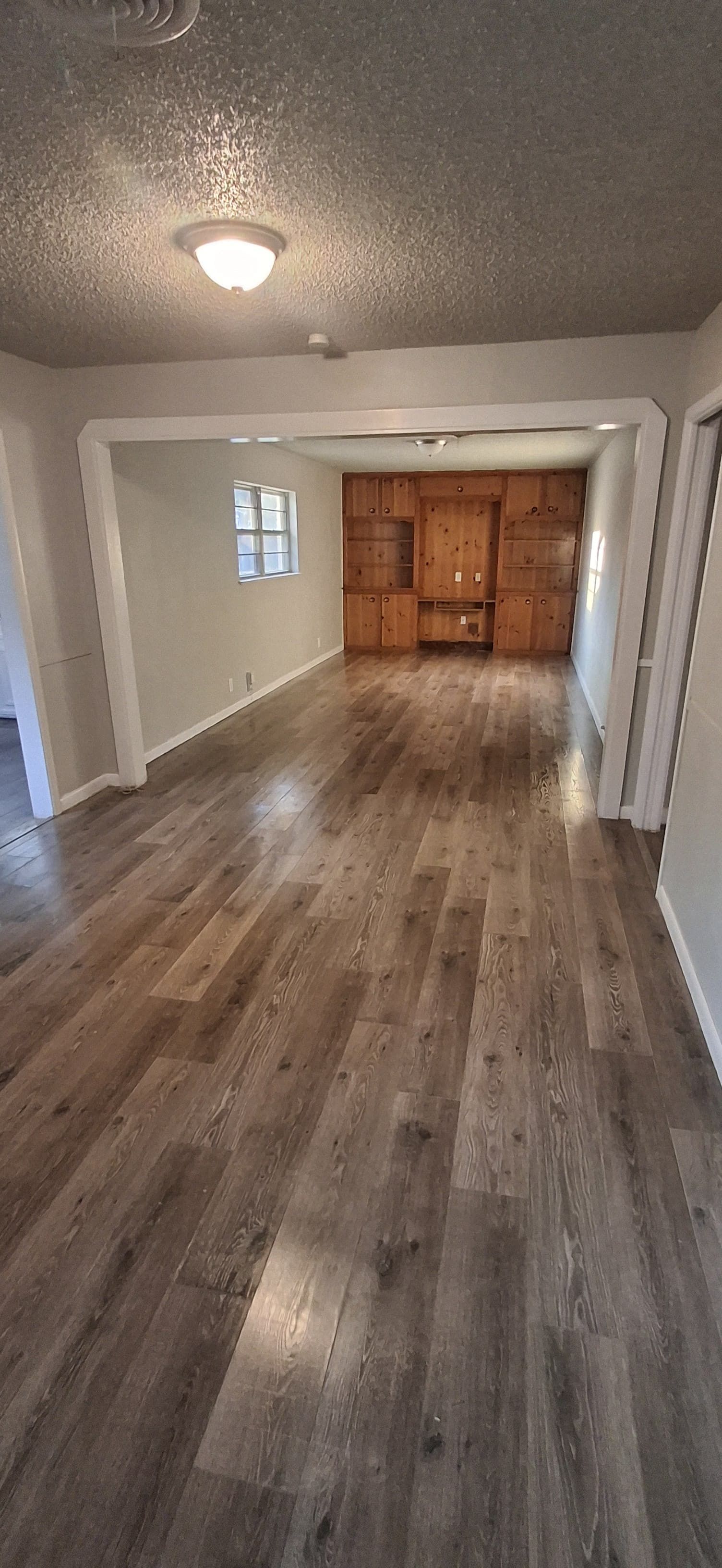 Interior view of a room with wood flooring, light walls, and built-in wooden cabinets.