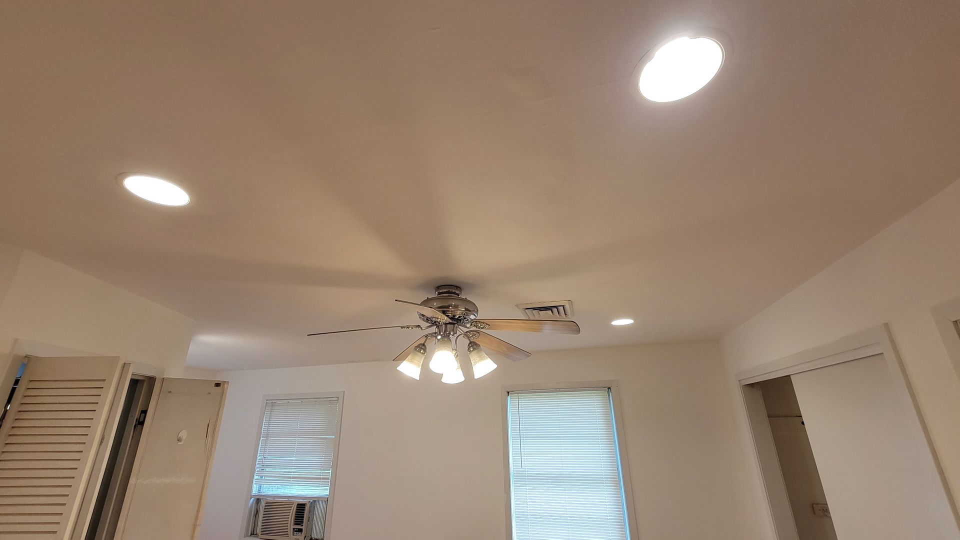 Ceiling with recessed lights, ceiling fan, and two windows with blinds.