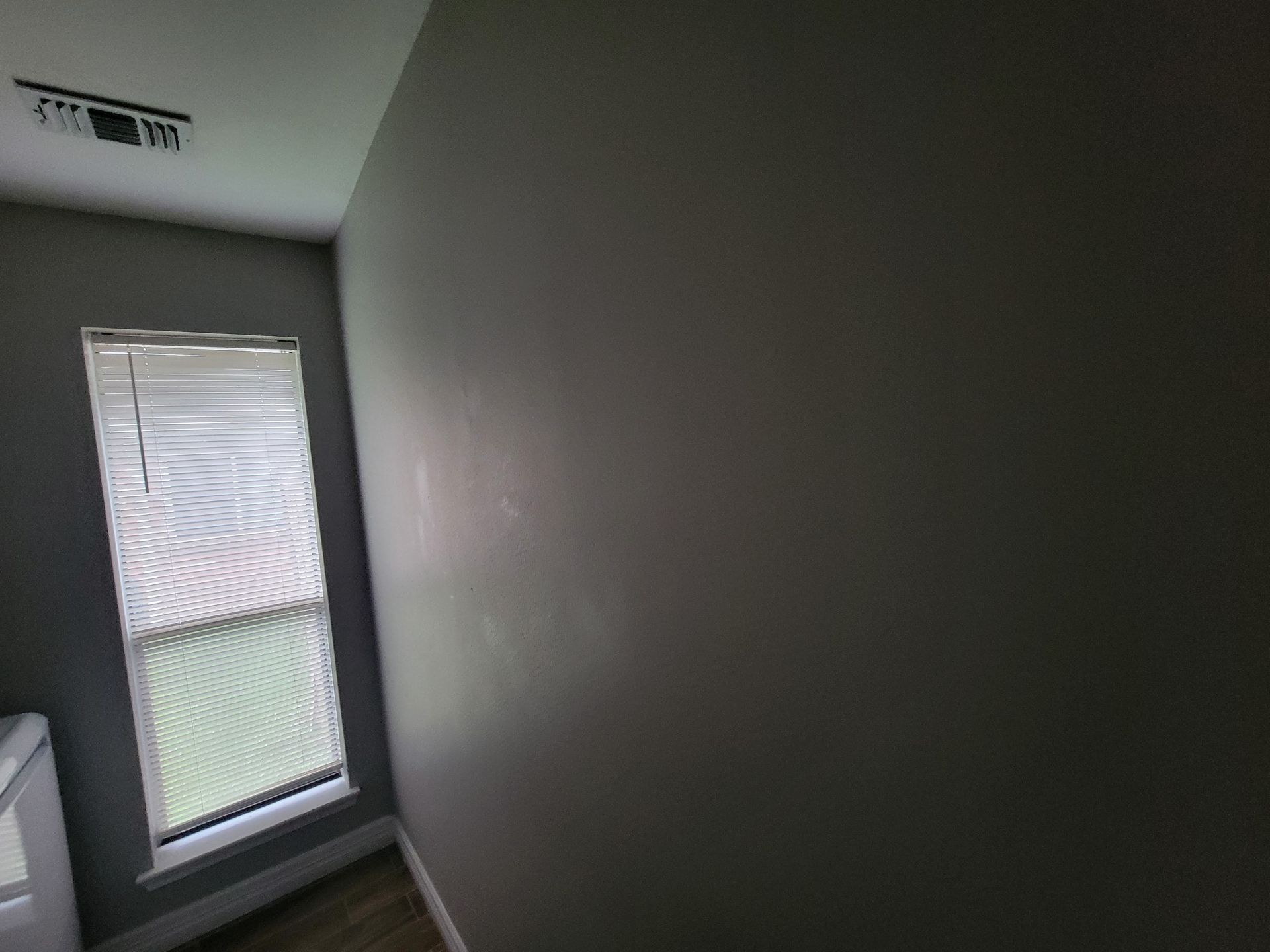 Interior view of a room with a window covered by blinds and gray walls.