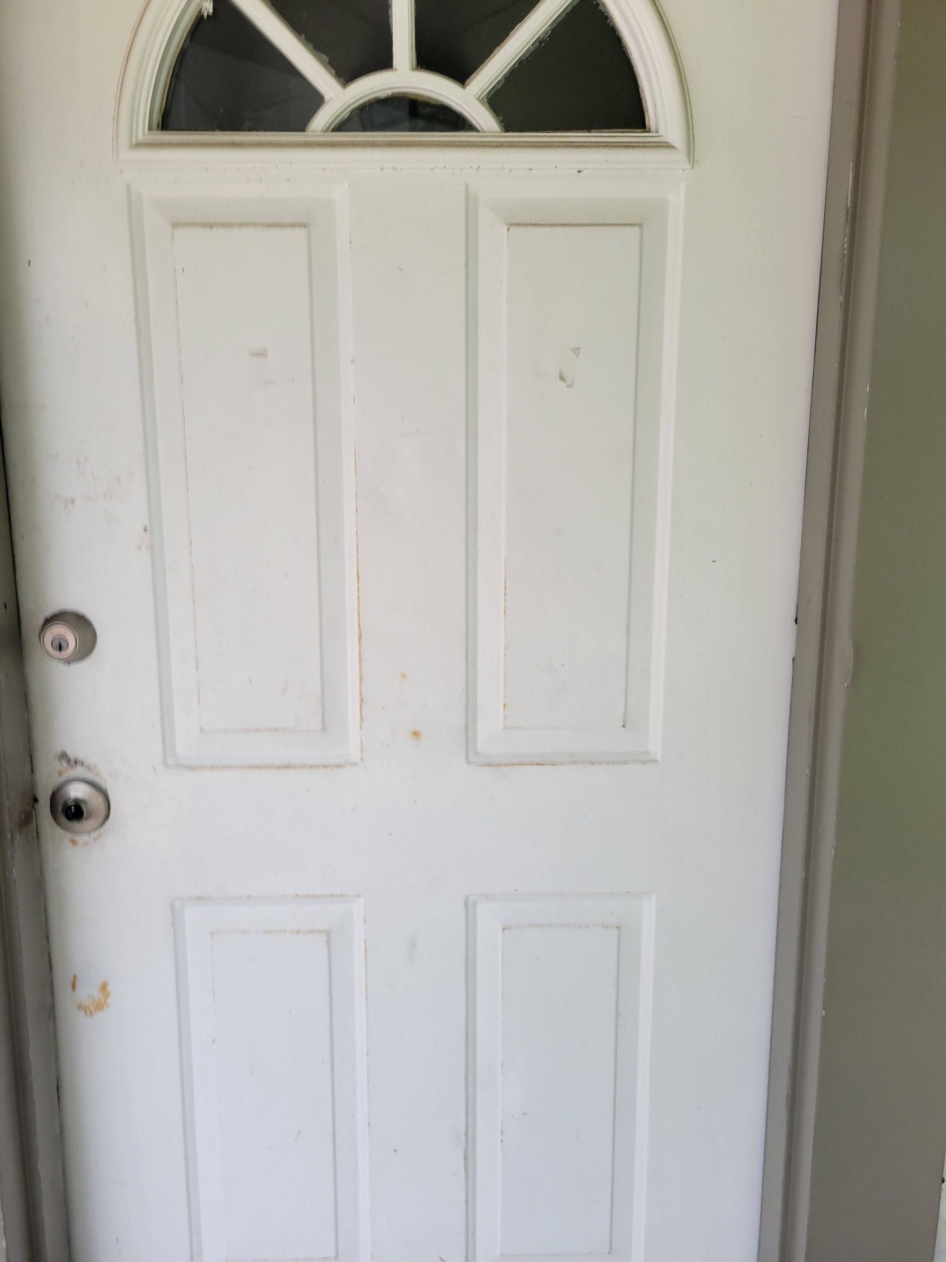 White exterior door with a window and two door knobs.