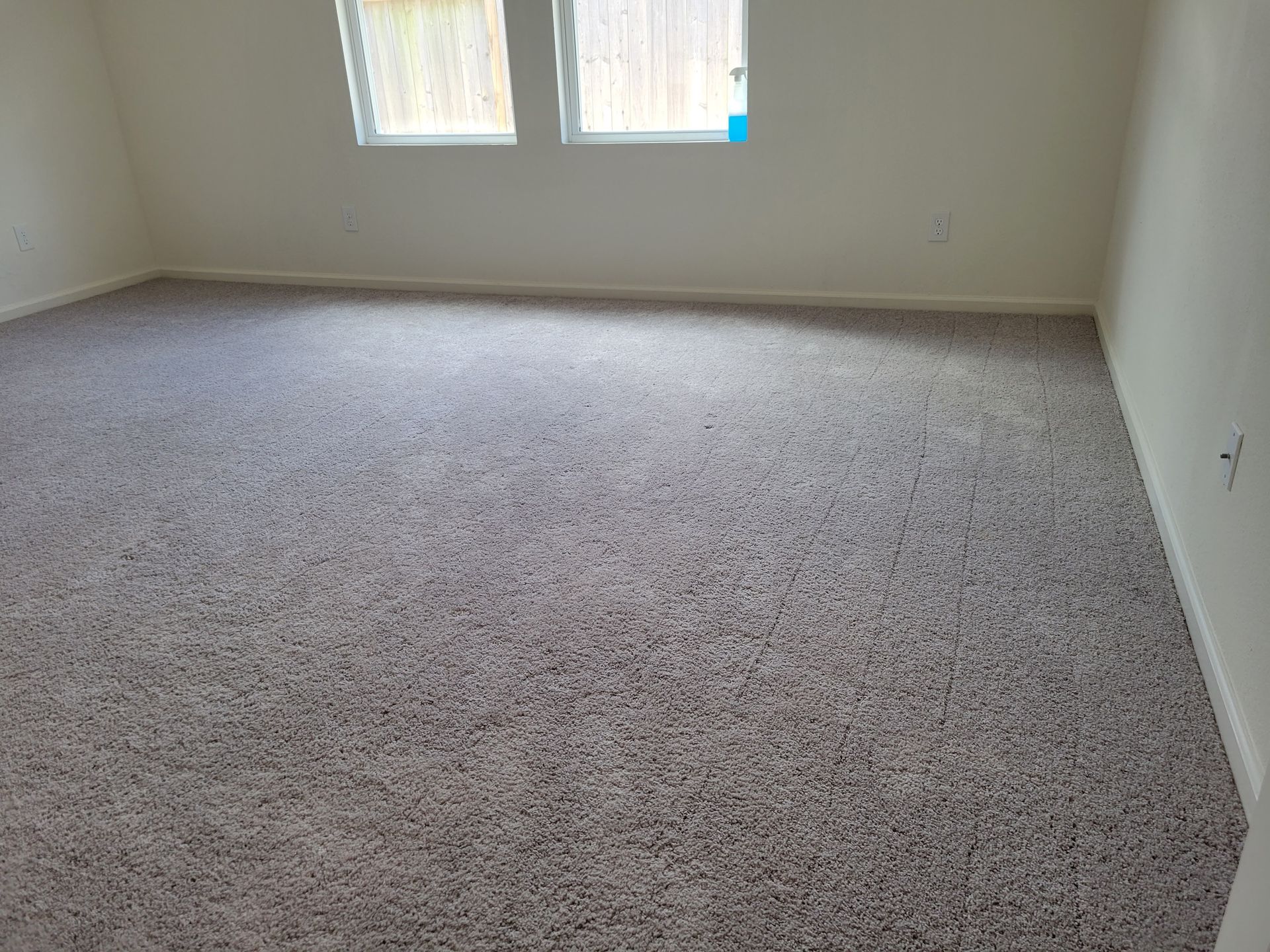 Empty room with gray carpet, two windows, and white walls.