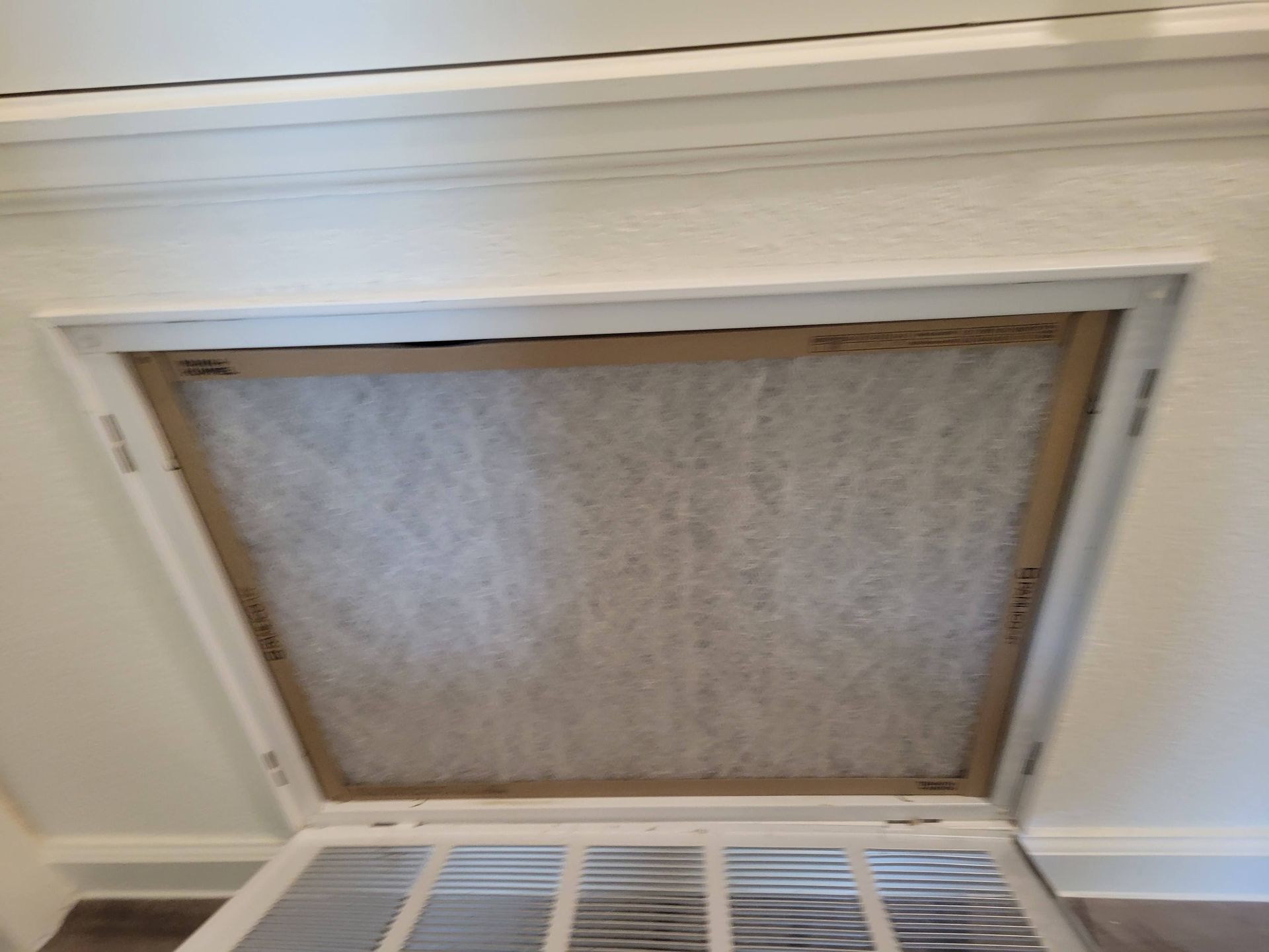 Open air filter in a white frame, inside a wall.