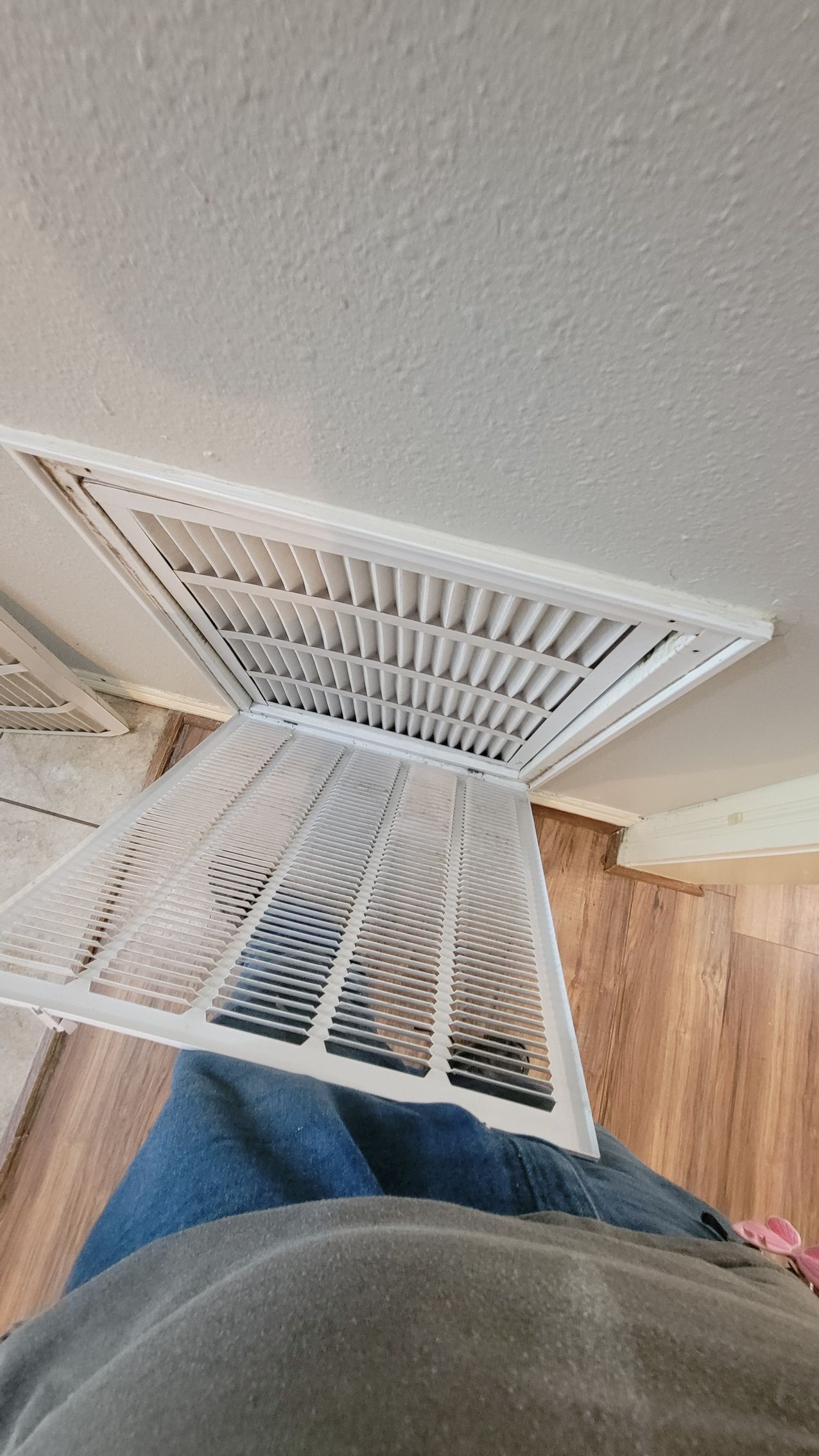 White air vent partially removed from a ceiling.