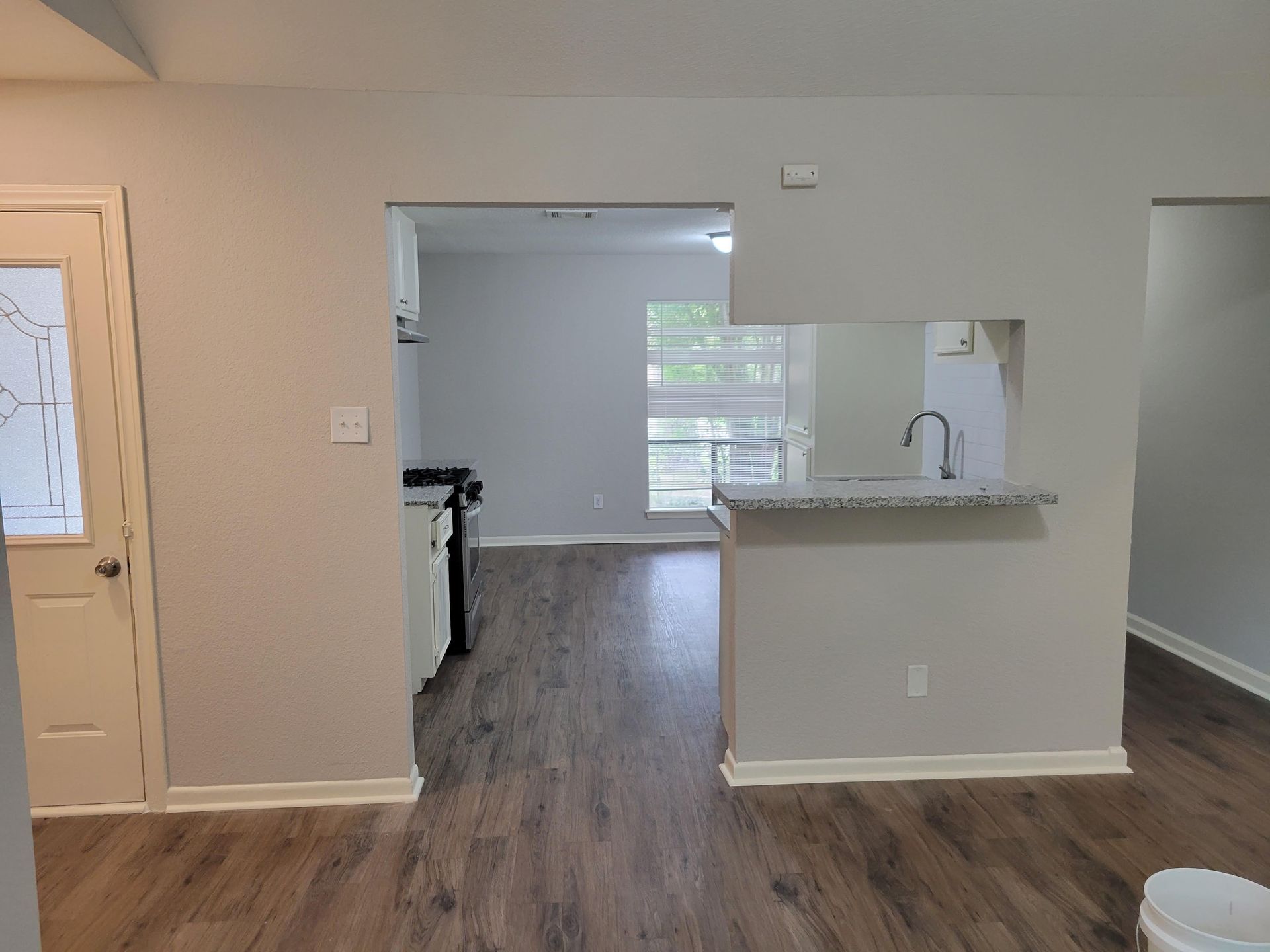 Interior view of an open-concept living space with gray walls, wood flooring, and a partial wall with a countertop.