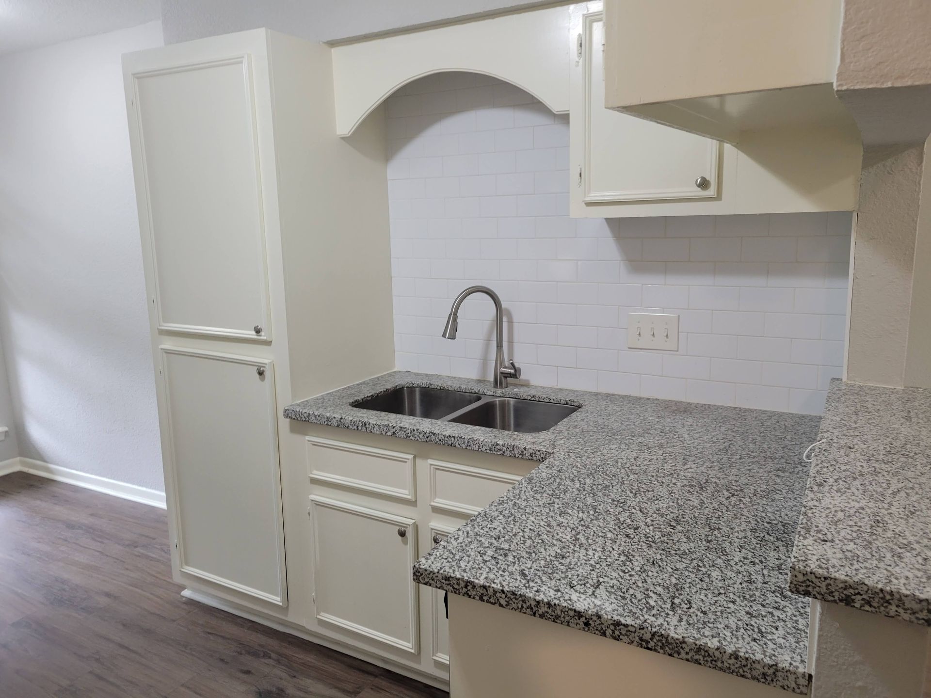 Kitchen with granite countertops, white cabinets, and stainless steel sink.