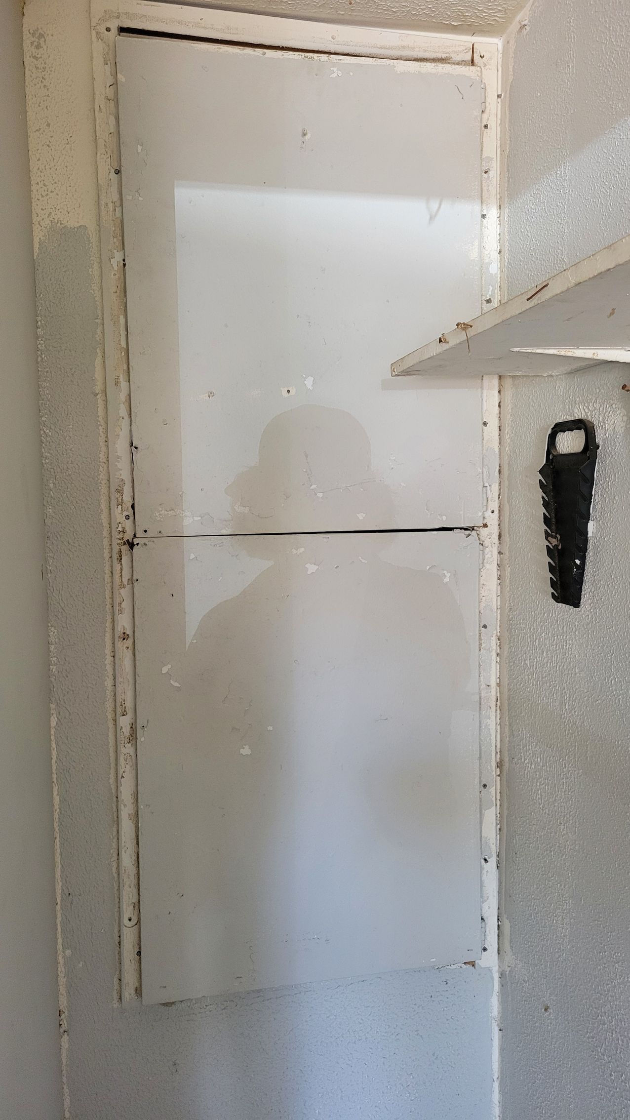 A white, fogged glass cabinet door in a shower. Black mold visible in the frame.