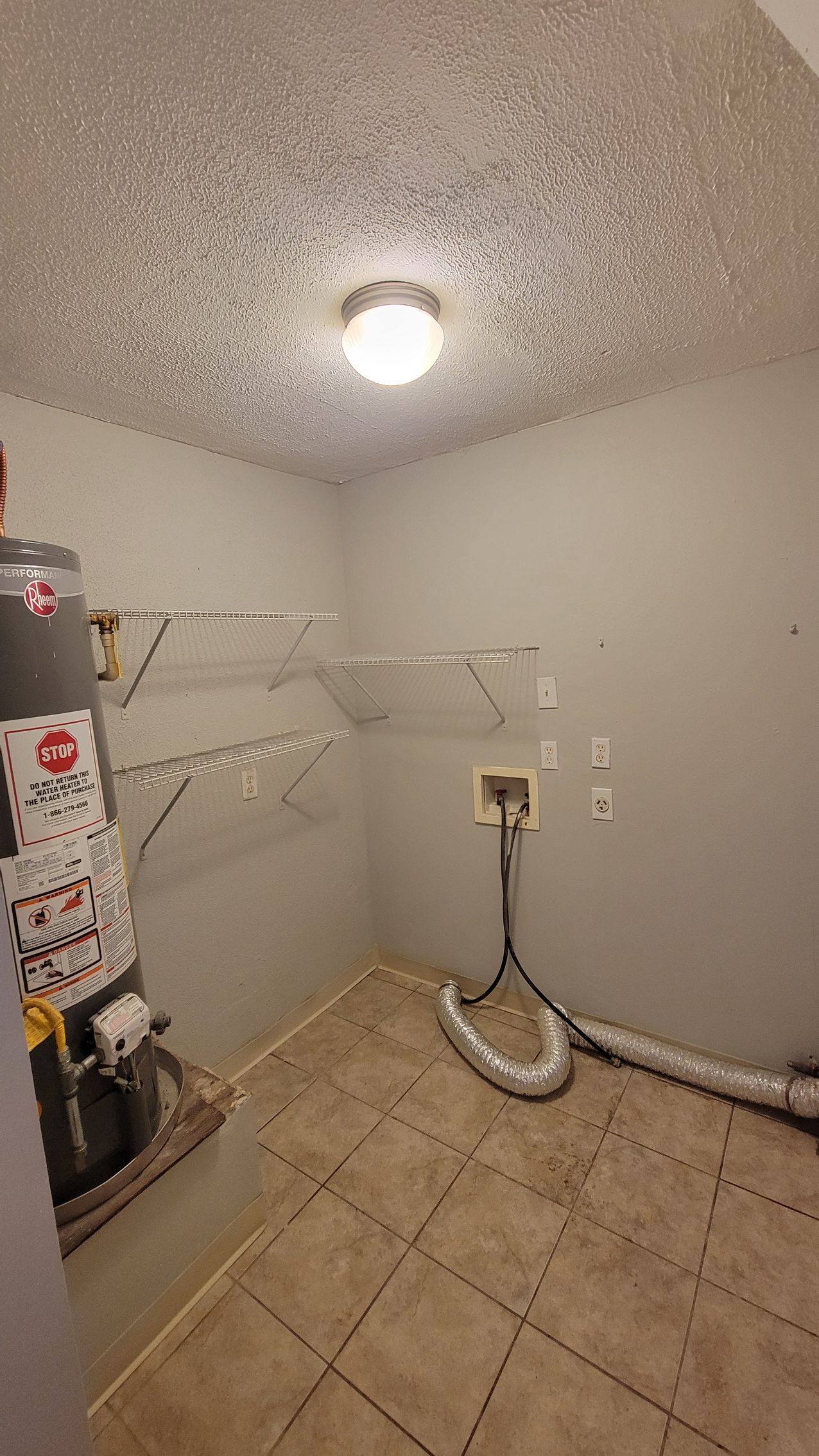 Laundry room with water heater, shelves, and dryer vent.