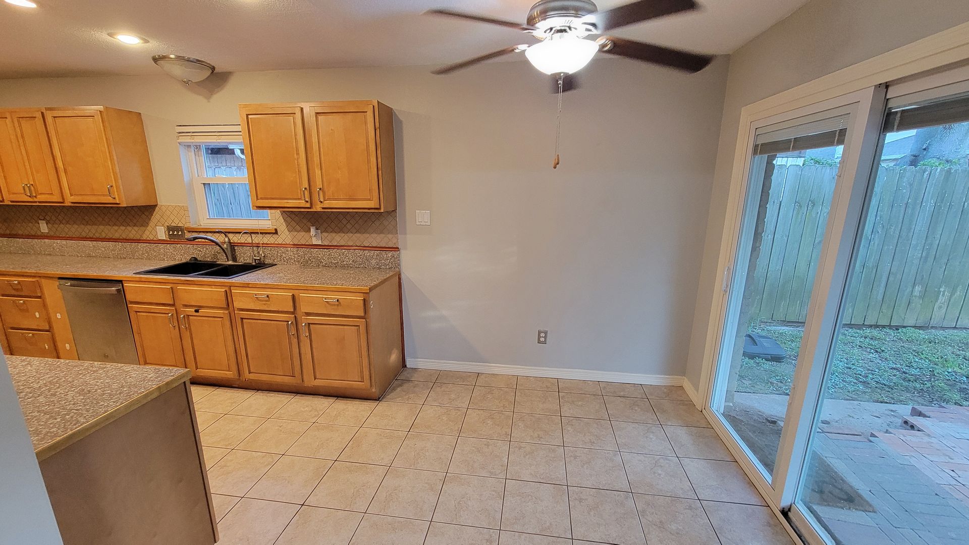 Kitchen with wooden cabinets, countertop, and a sliding glass door.