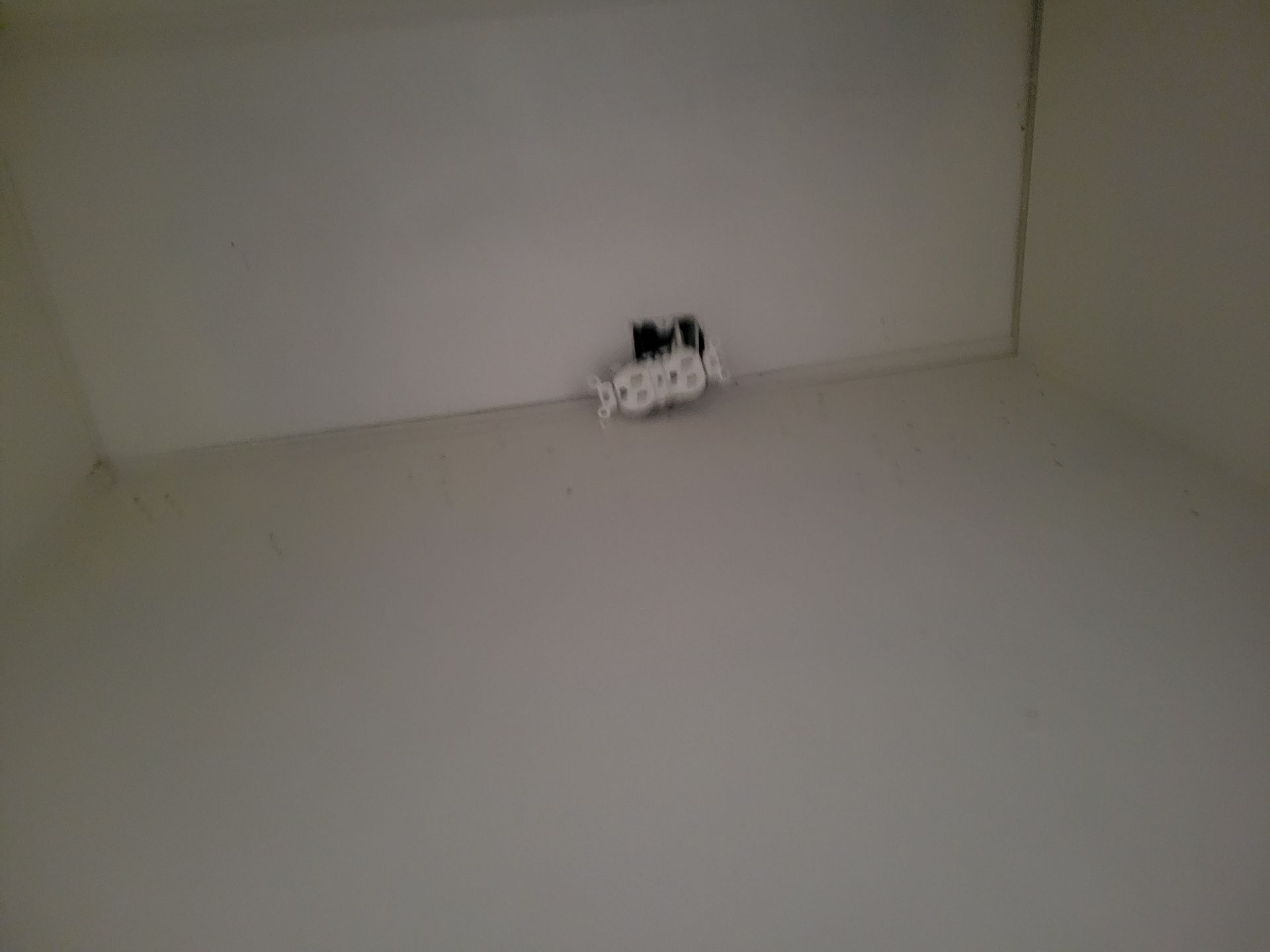 A blank, white room with a cable outlet on the ceiling.