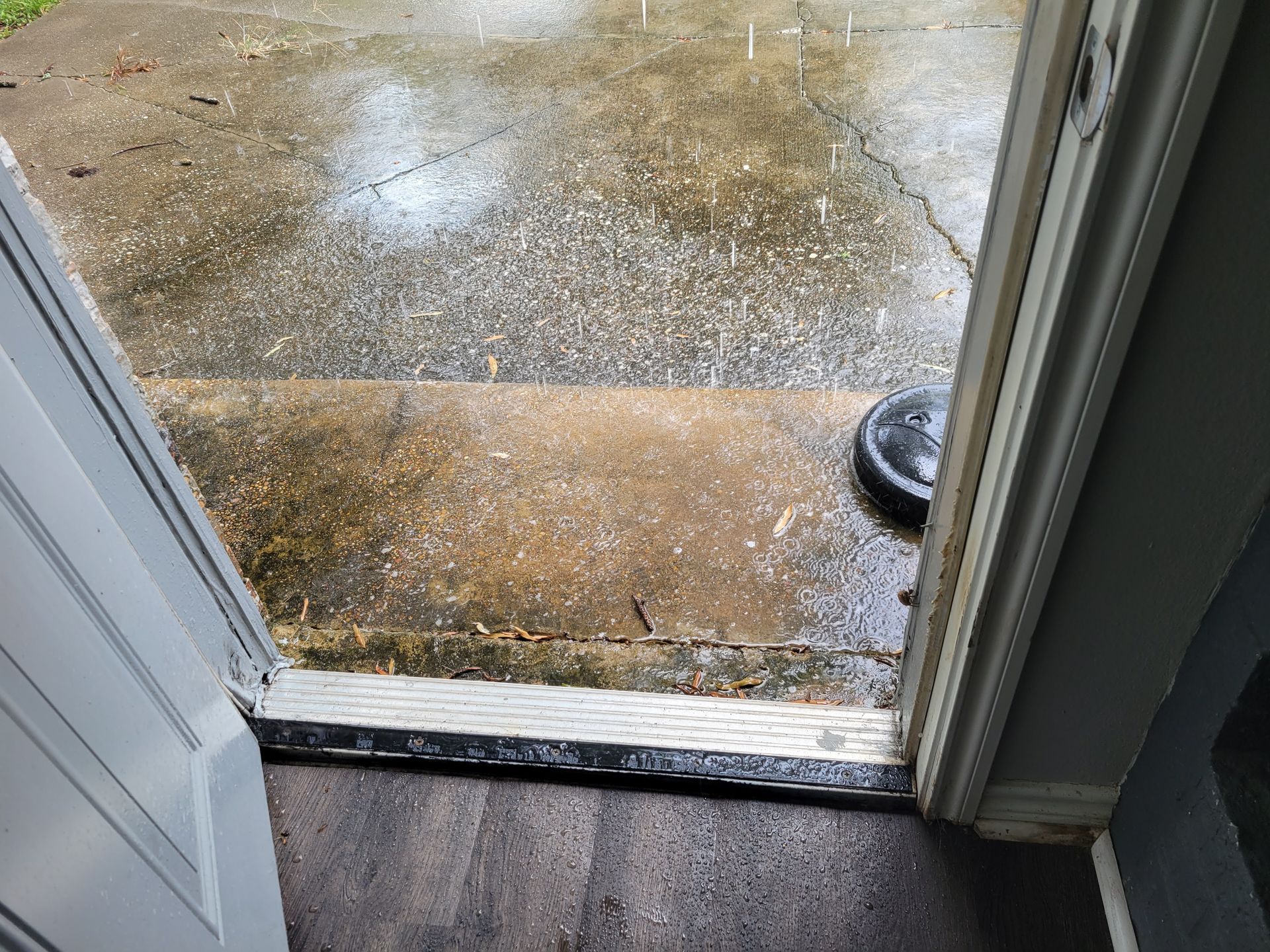 Open doorway to wet concrete porch. Door threshold visible.