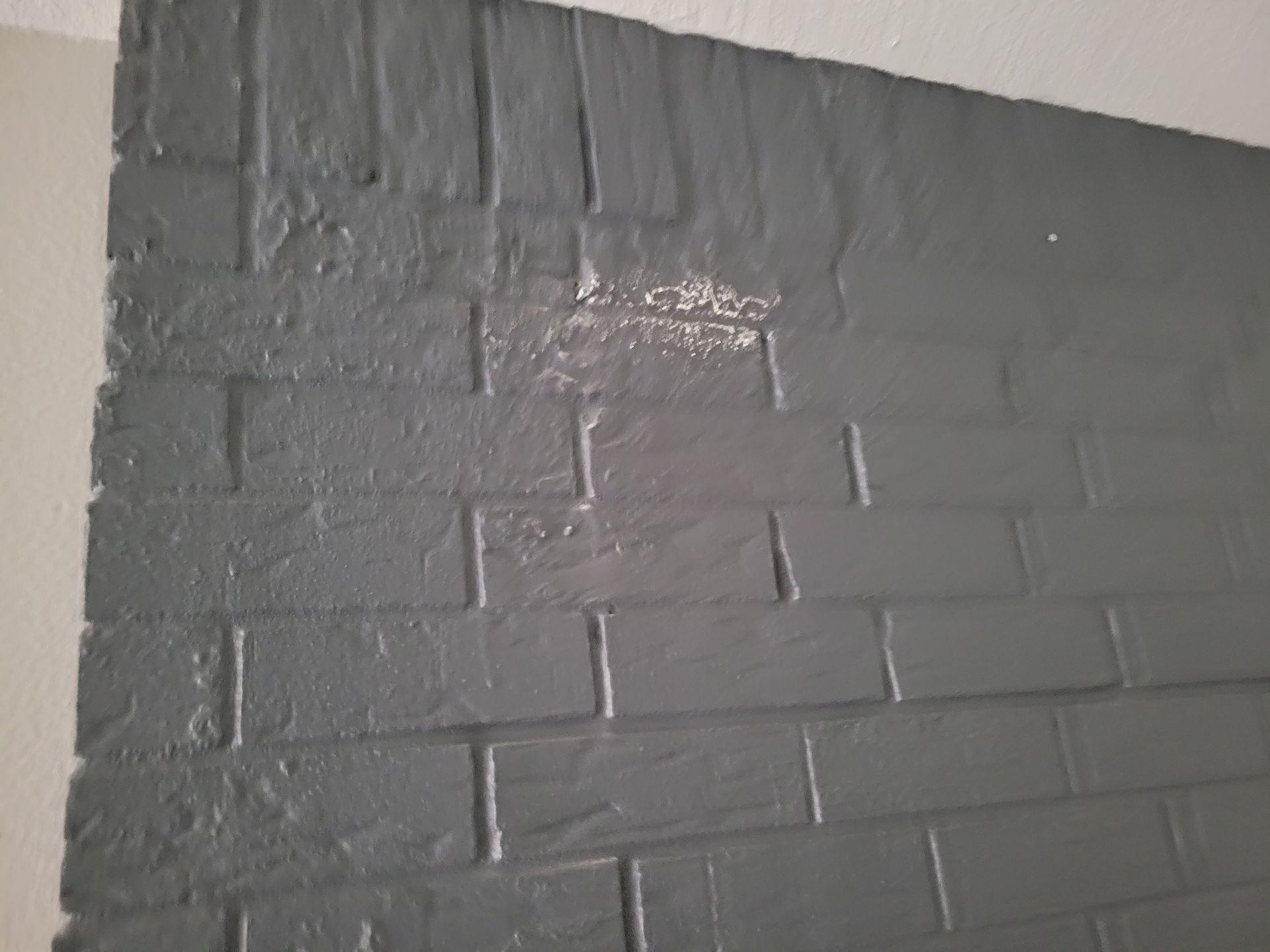 Gray painted brick wall with paint peeling.