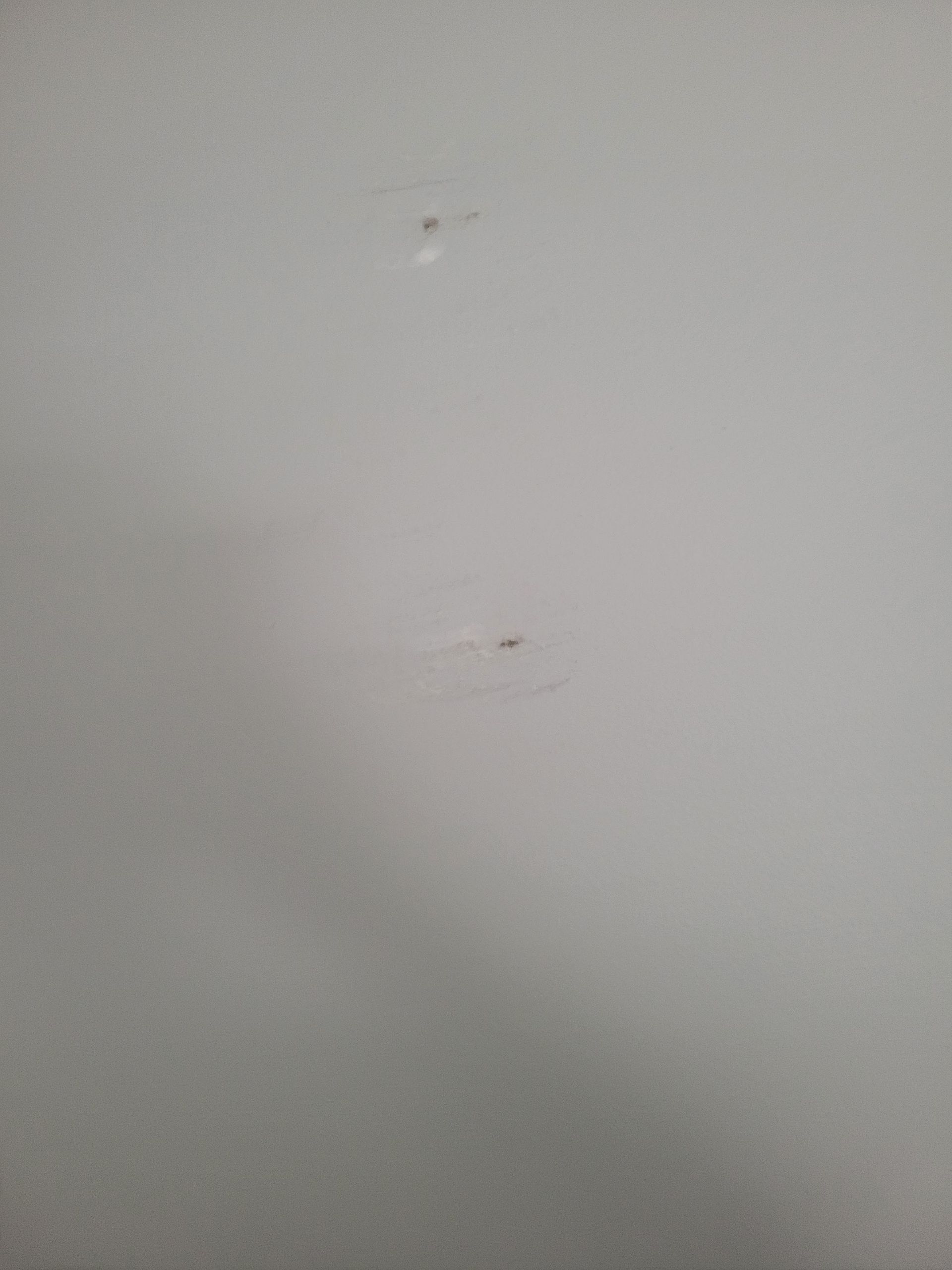 Two small holes on a white wall.