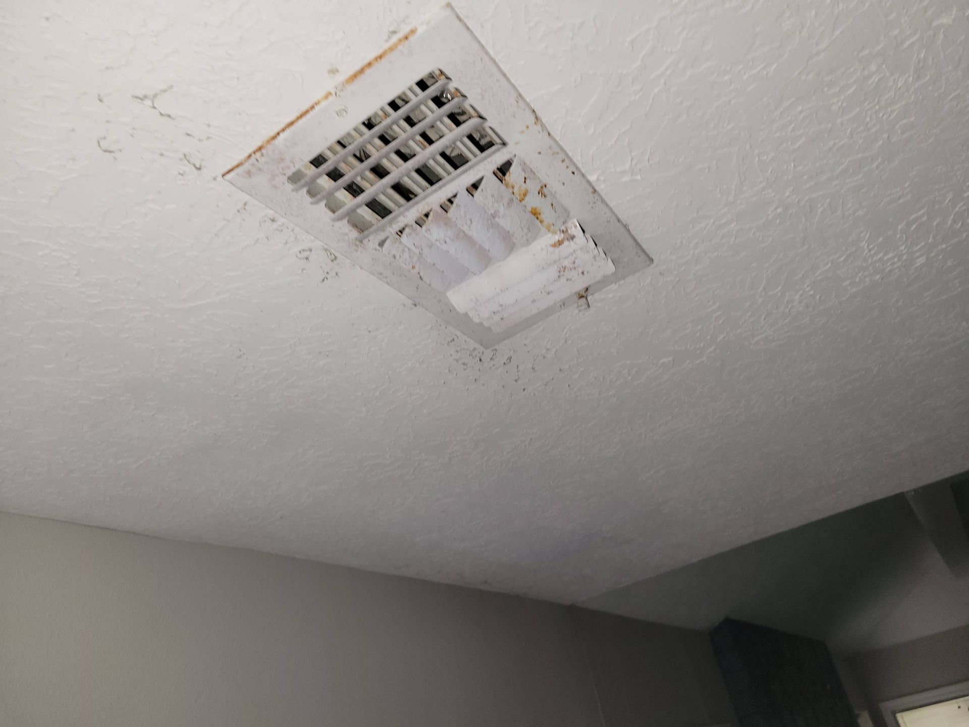 Ceiling vent with visible dirt and debris, set in a white textured ceiling.