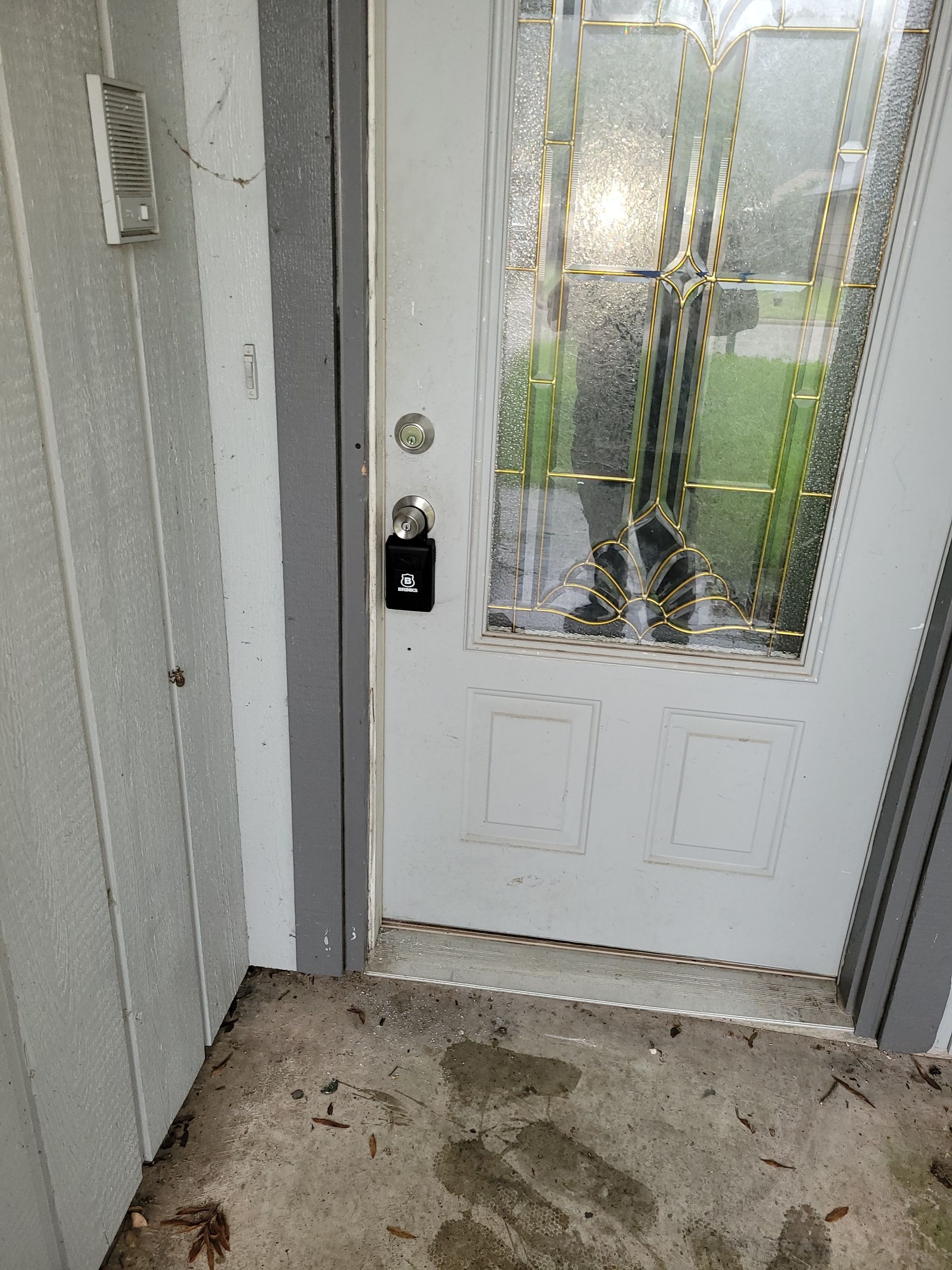 White front door with glass panes and a lockbox, viewed from outside.