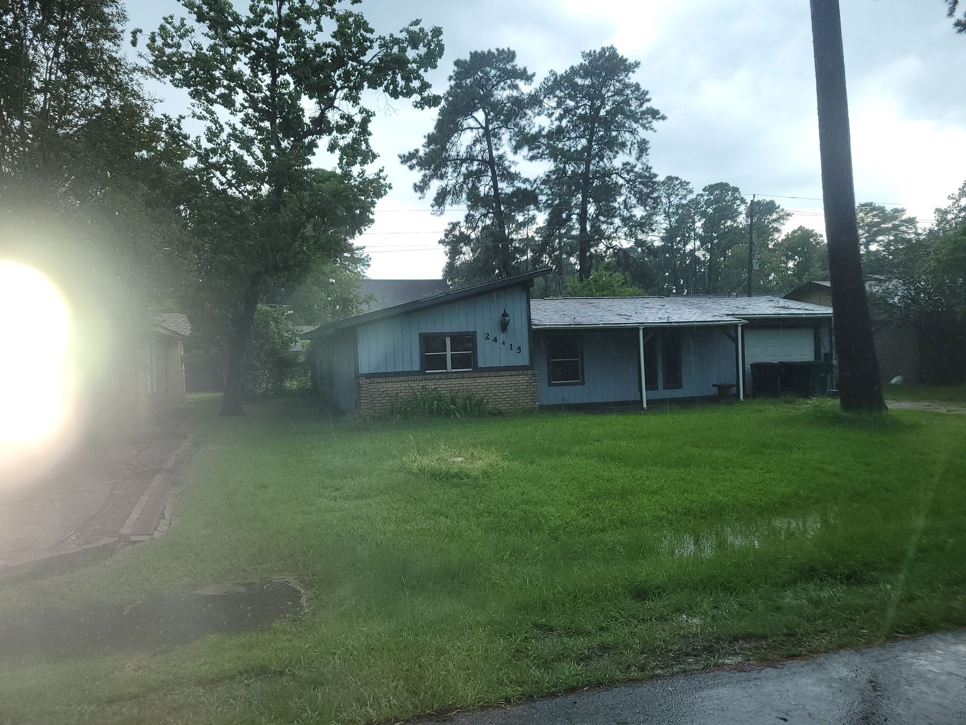 Blue house with brick facade and green lawn on a cloudy day.