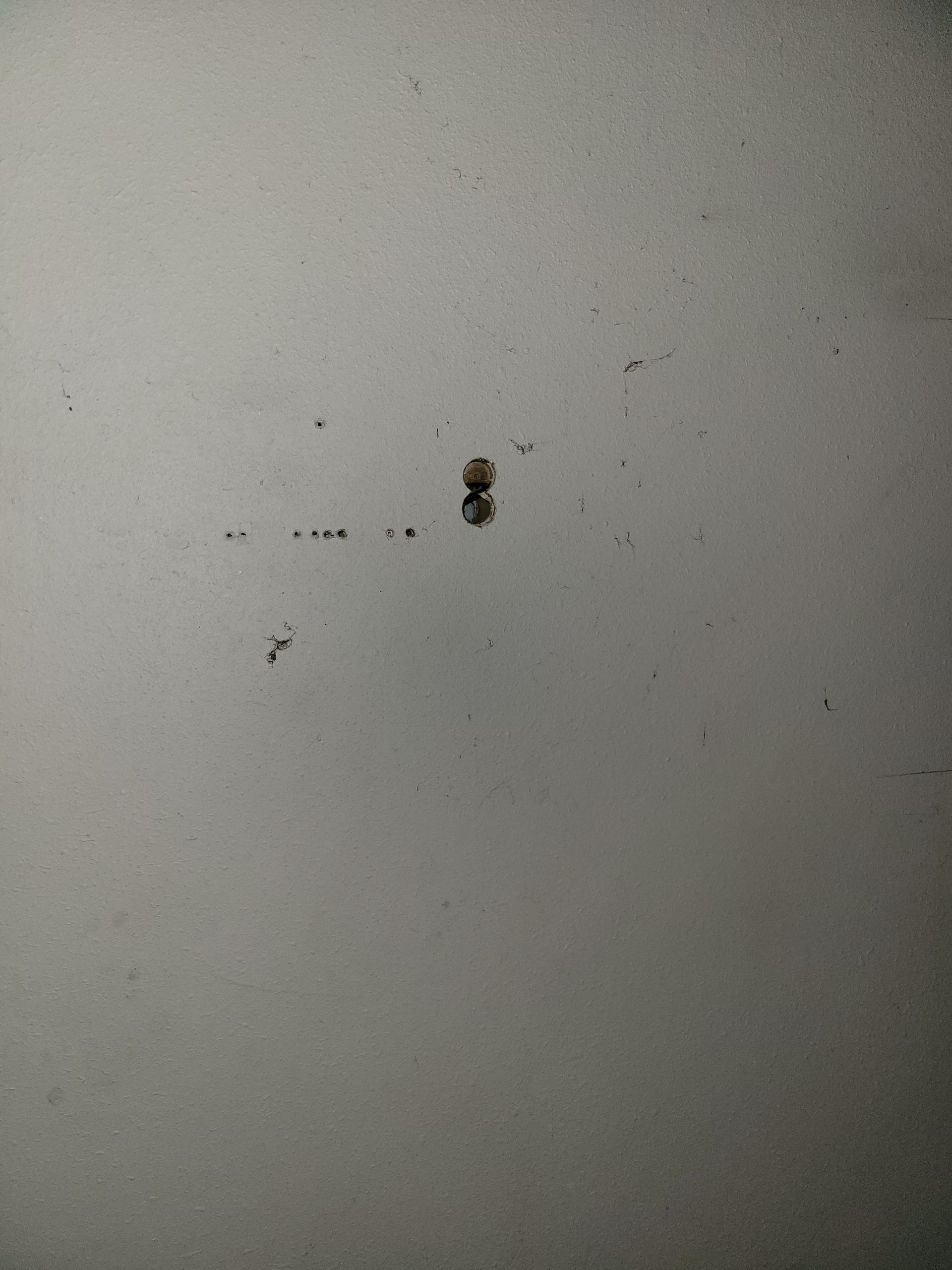 White surface with small dark specks and a larger, brown, raised spot.