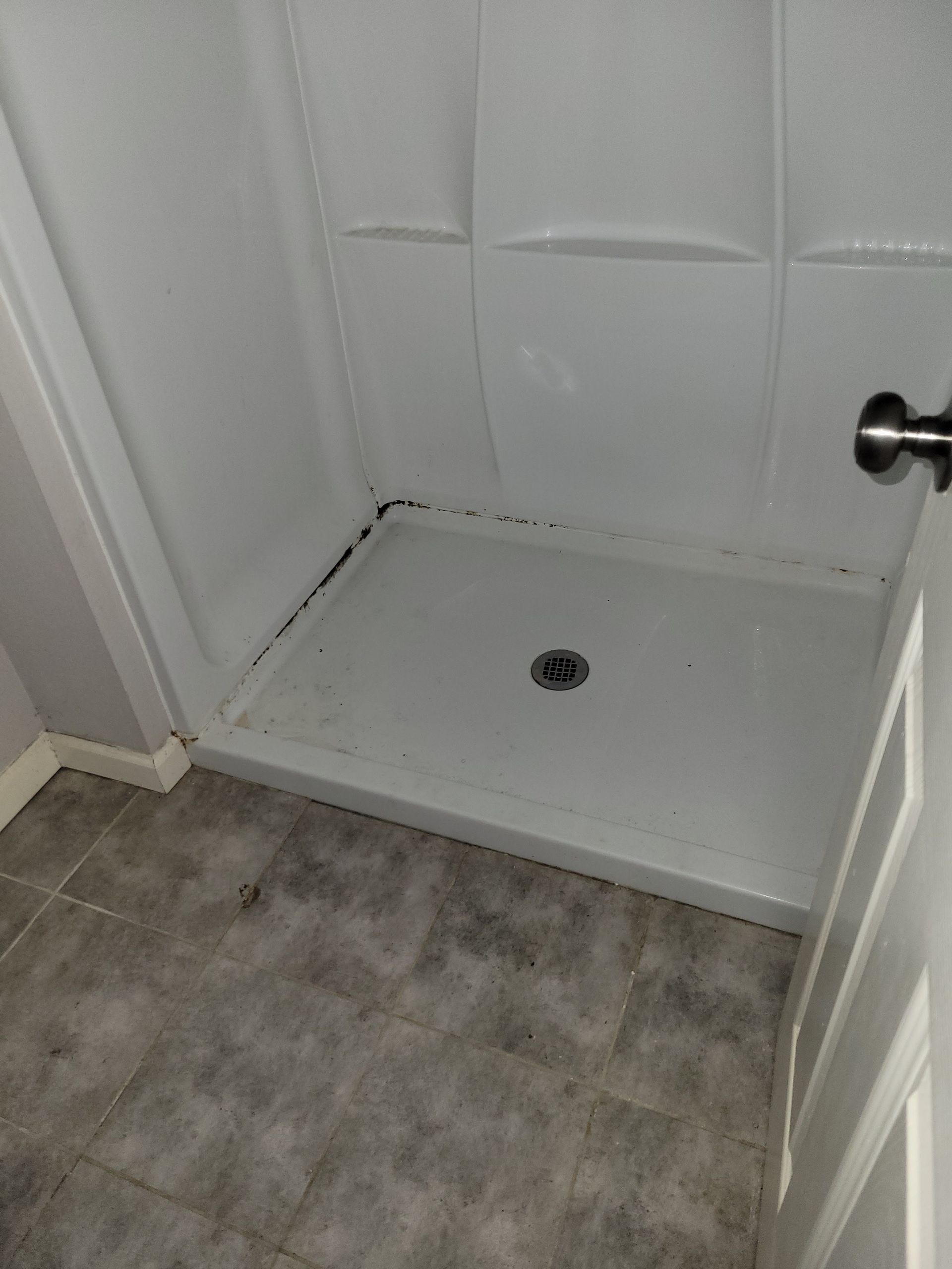 White shower stall with a gray tile floor.