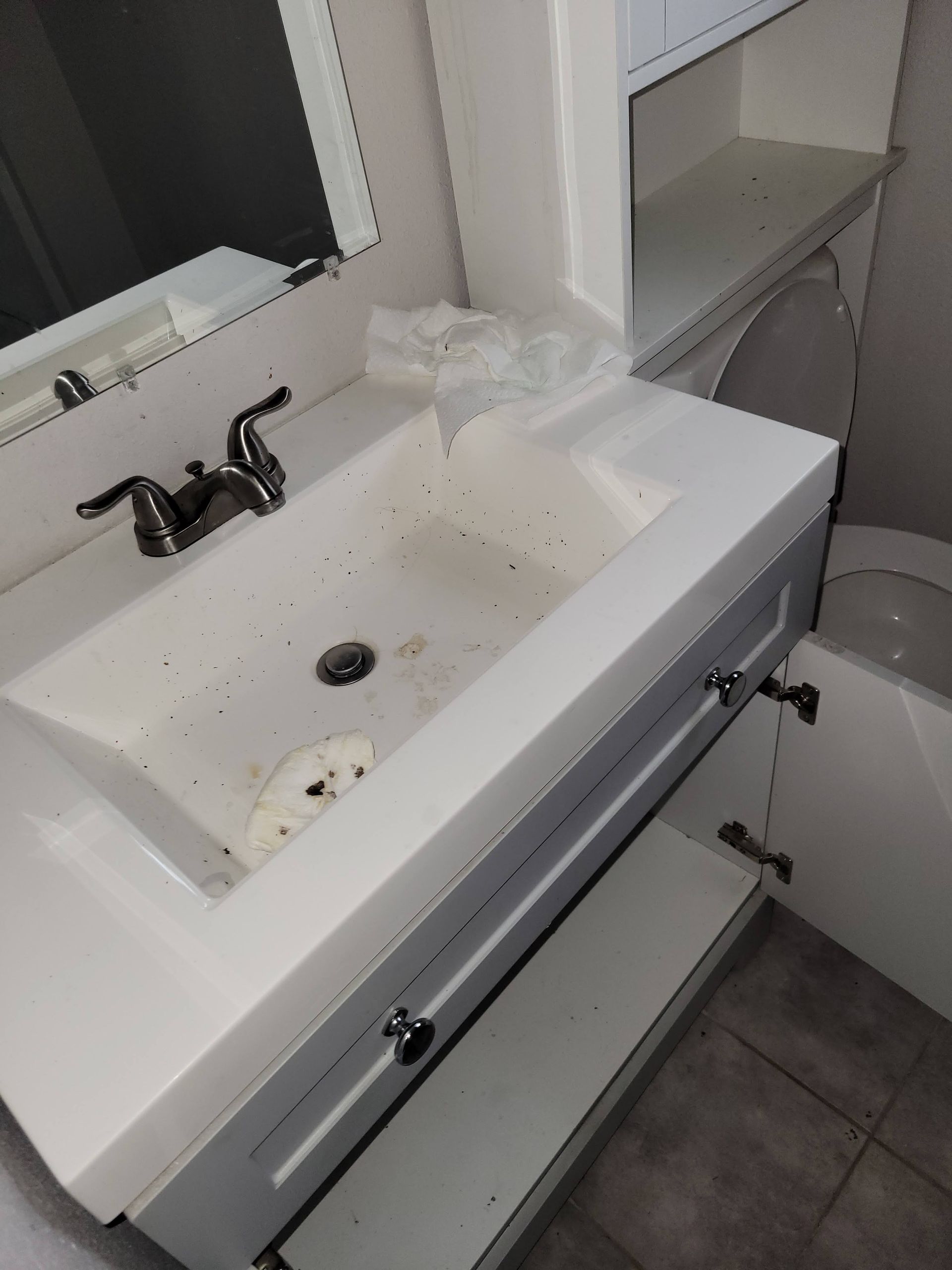 Bathroom sink and vanity with dark-colored faucet, gray cabinets, and a white countertop.
