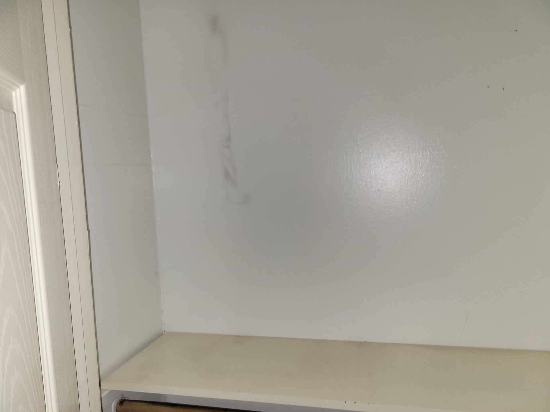 White interior wall with a shelf. A stain runs down the wall.