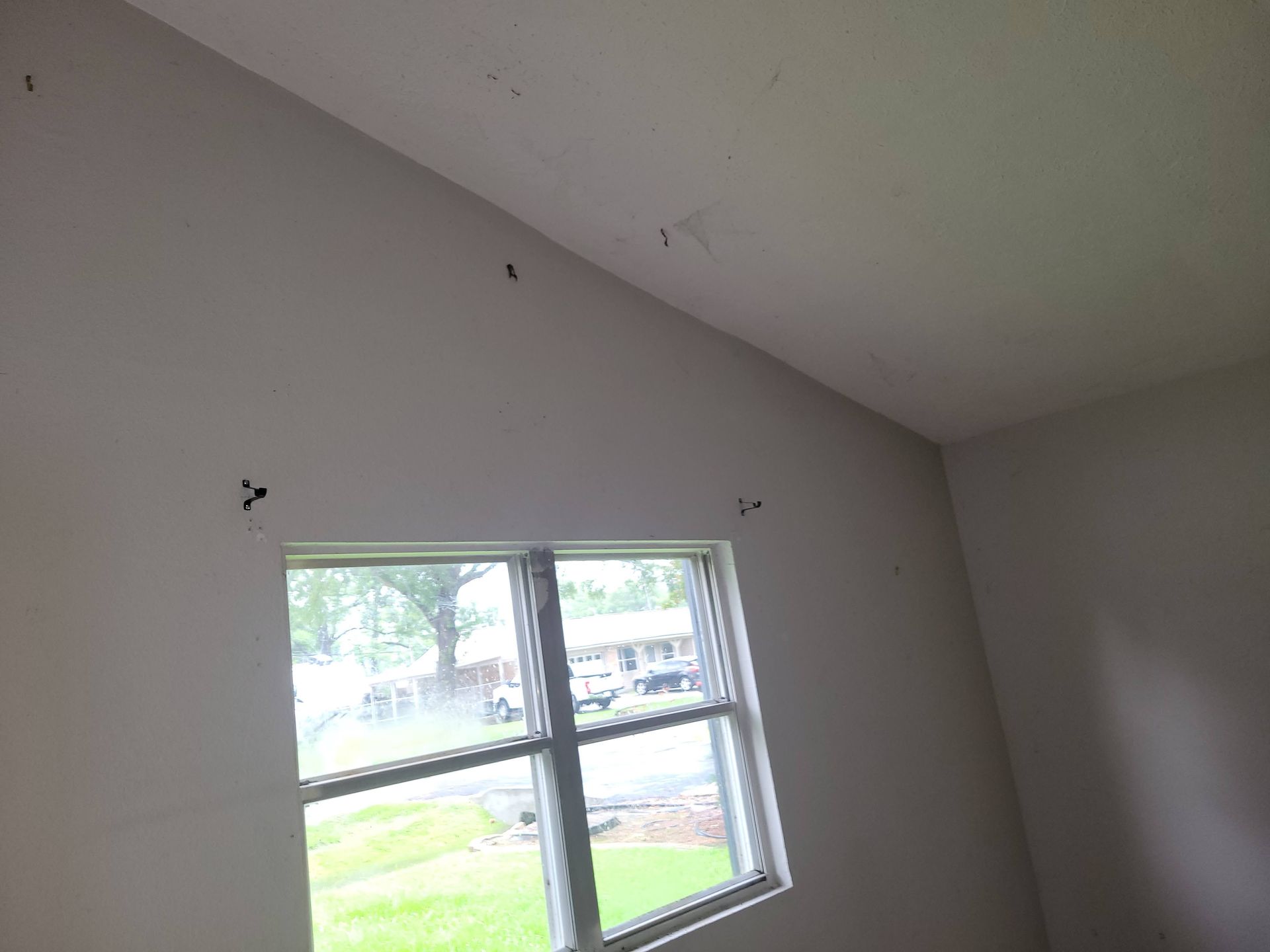 Interior view of a room with a window, white walls, and a sloped ceiling.