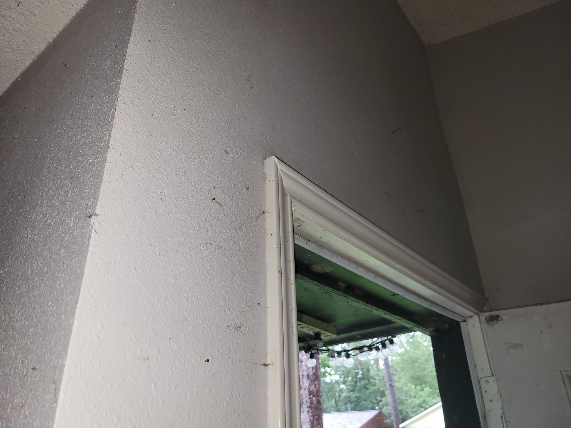 Interior view of a door frame and surrounding textured walls, painted white.