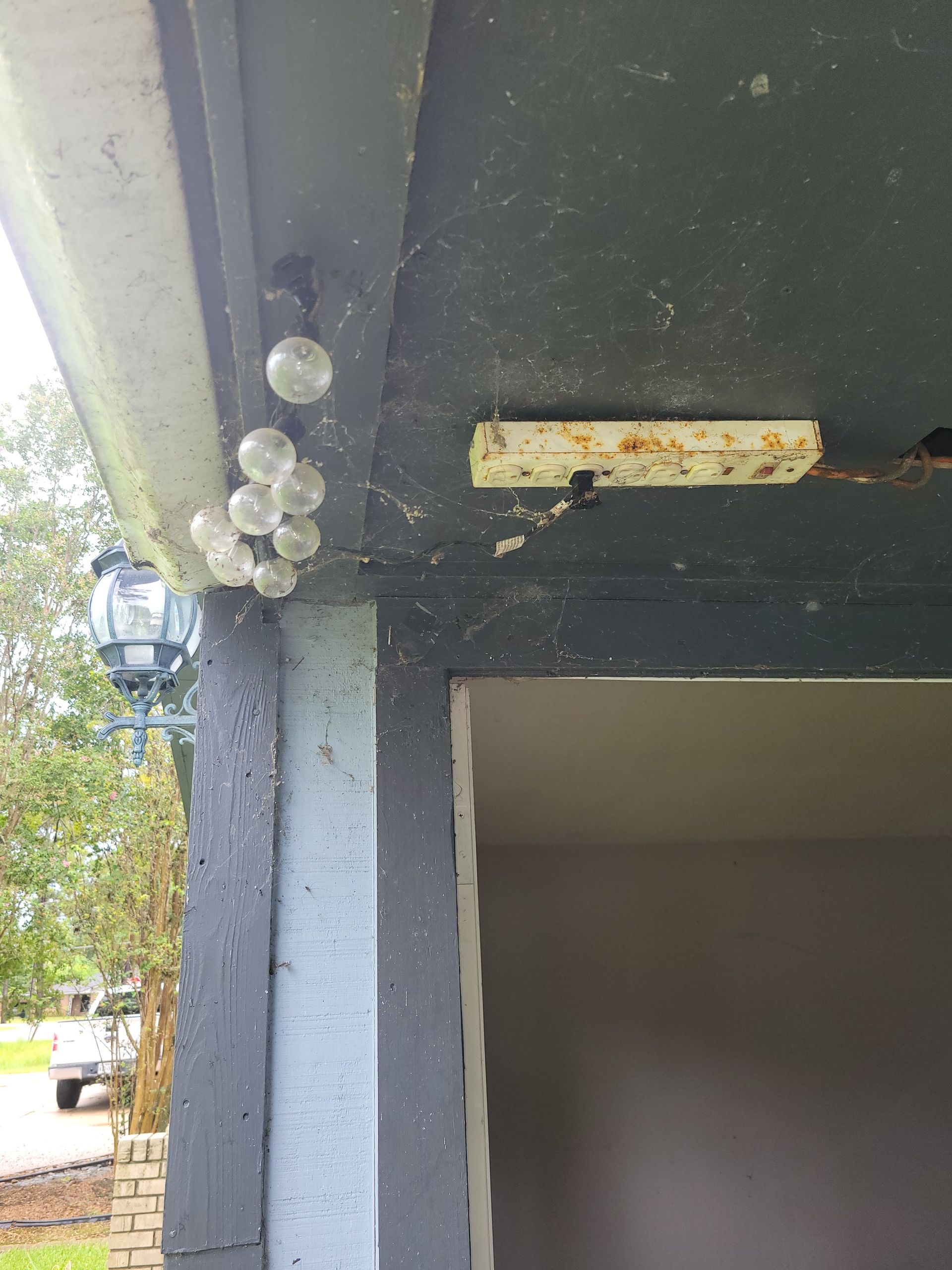 Exterior view with clear, round lights clustered near the ceiling of a porch.