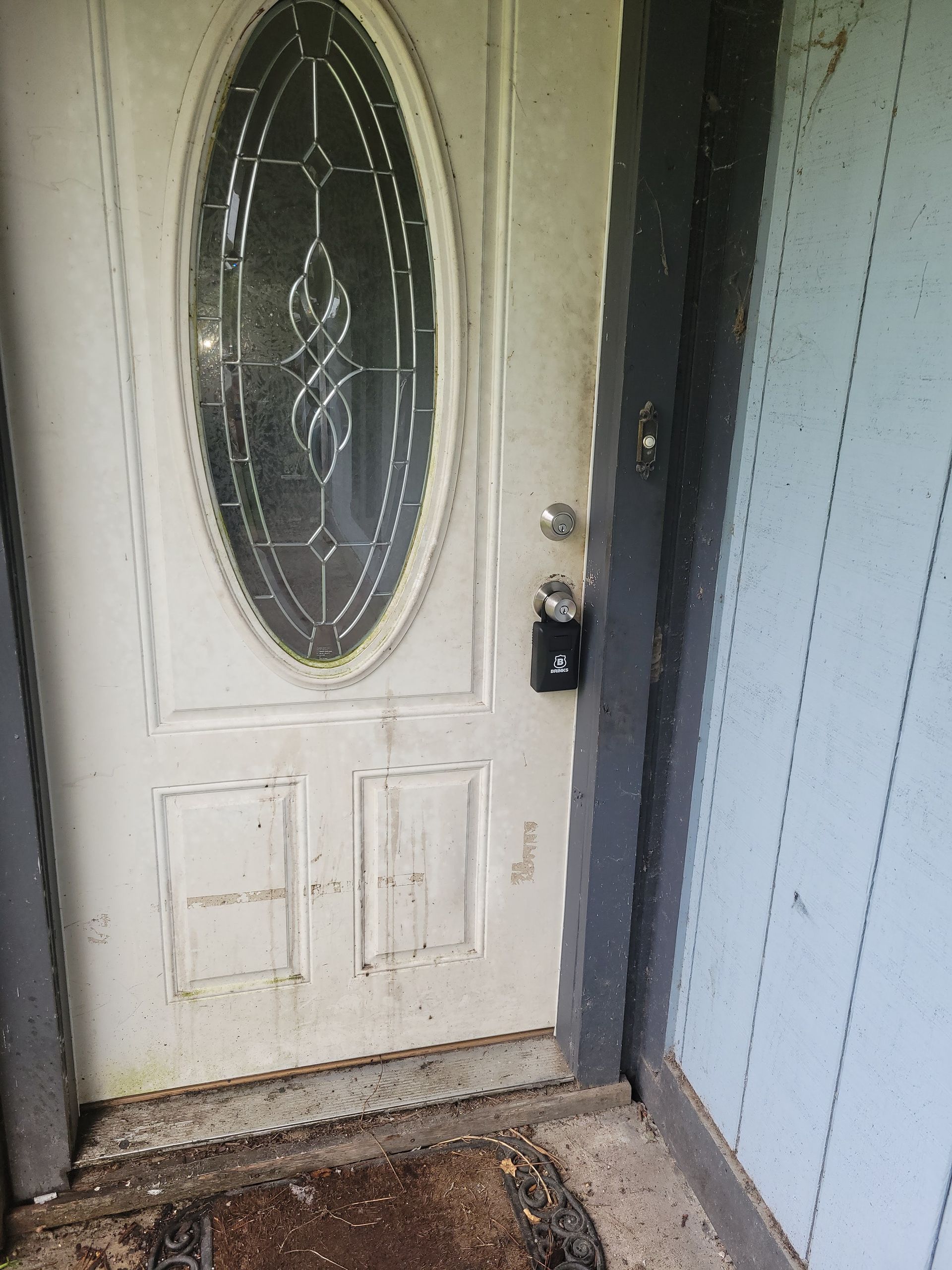 White exterior door with oval window, lock and doormat.