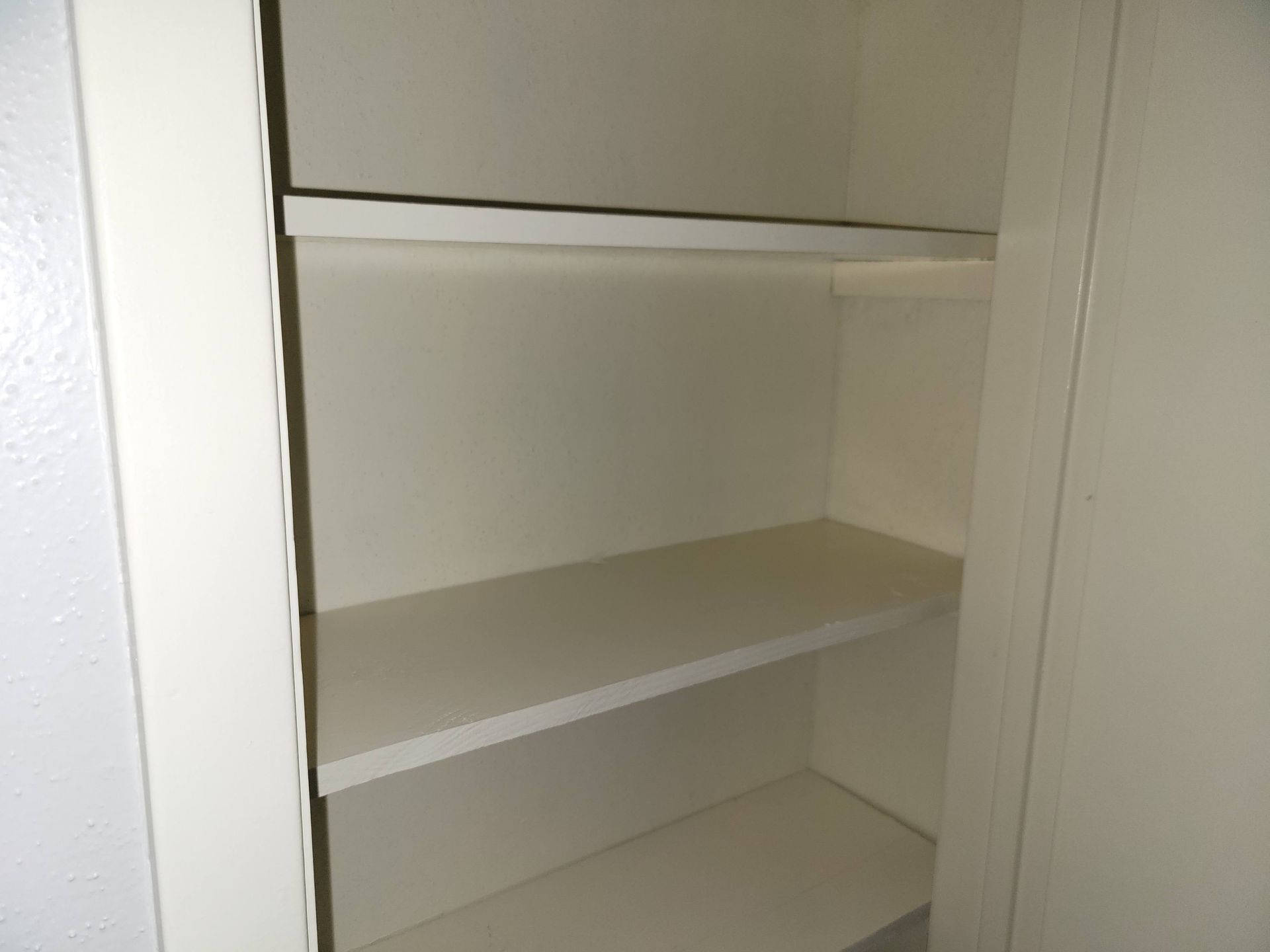 Empty white closet with three shelves and a rod.
