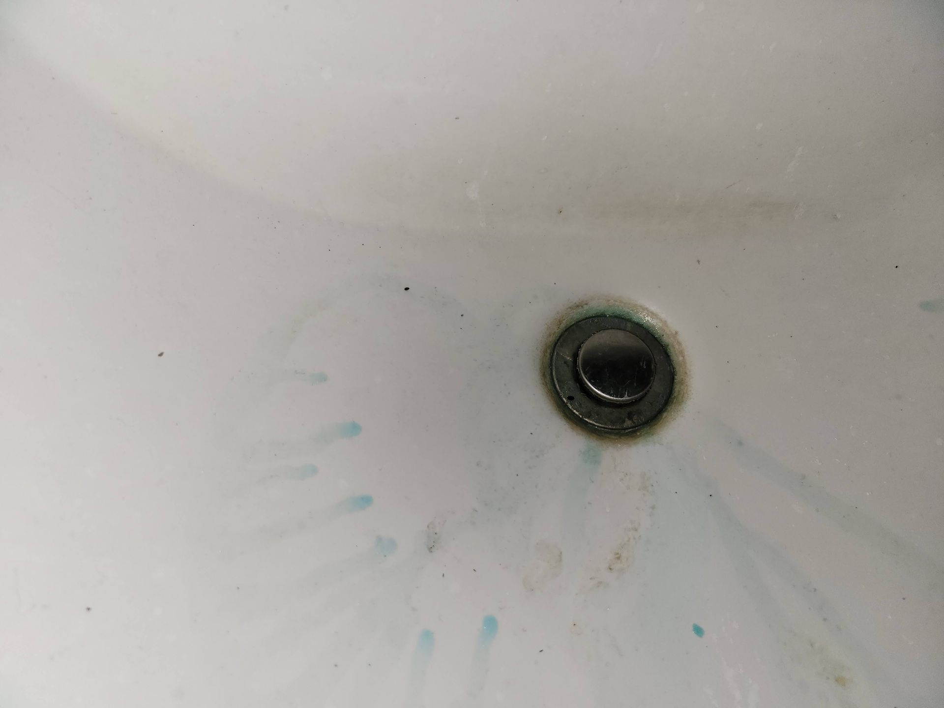 White sink with drain and blue streaks.