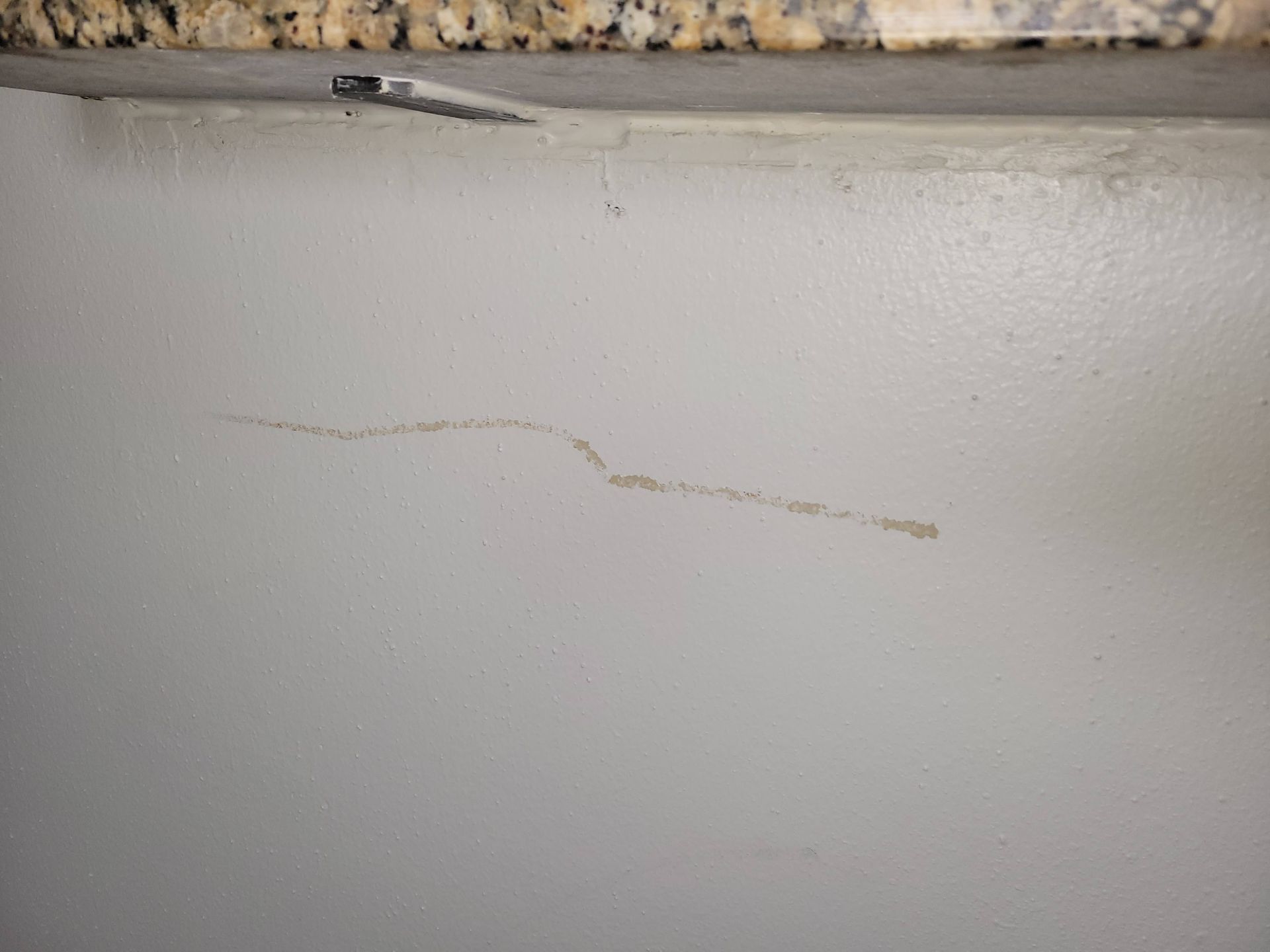 White wall with a brown stain or streak below a counter.