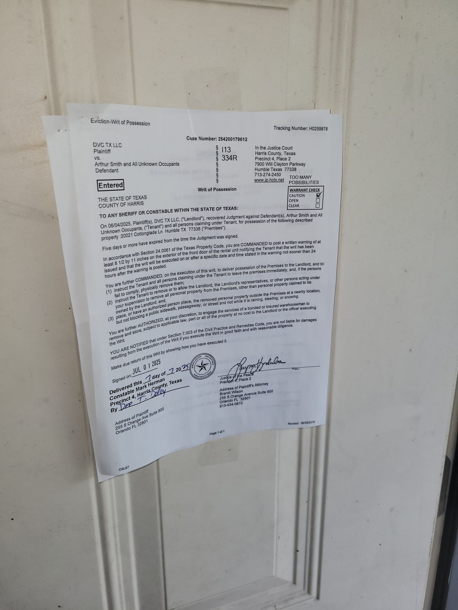 White door with a paper document attached, likely a notice or legal document with text and markings.