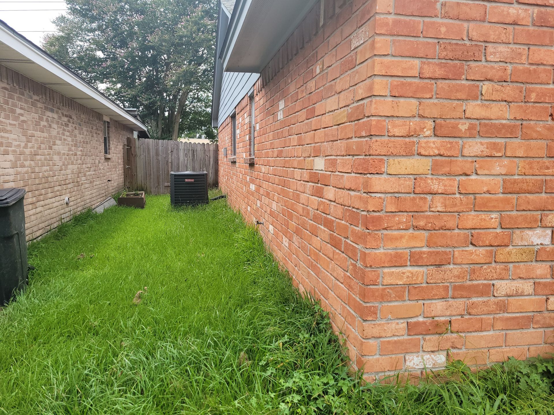 Red brick building side next to a grassy area and a smaller building.