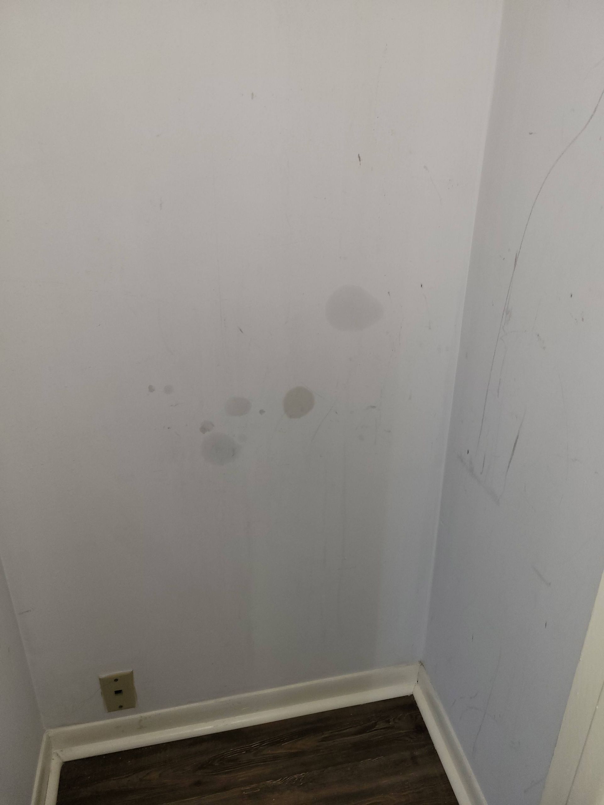 White interior wall with several dark stains near the bottom corner. A power outlet is visible.