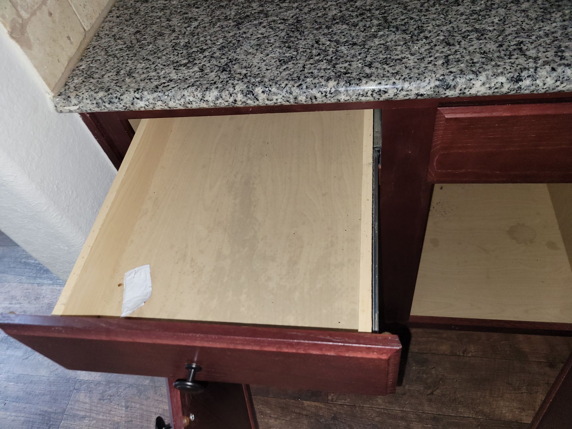 Open burgundy kitchen drawer under granite countertop.