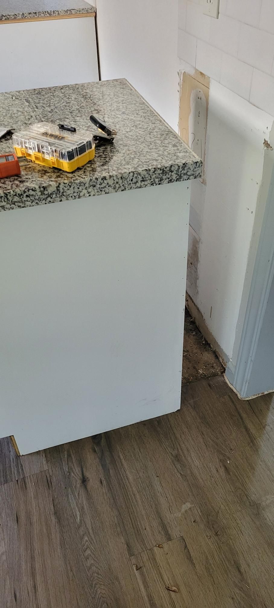 A white kitchen cabinet with a gray granite countertop; tools rest on the counter.