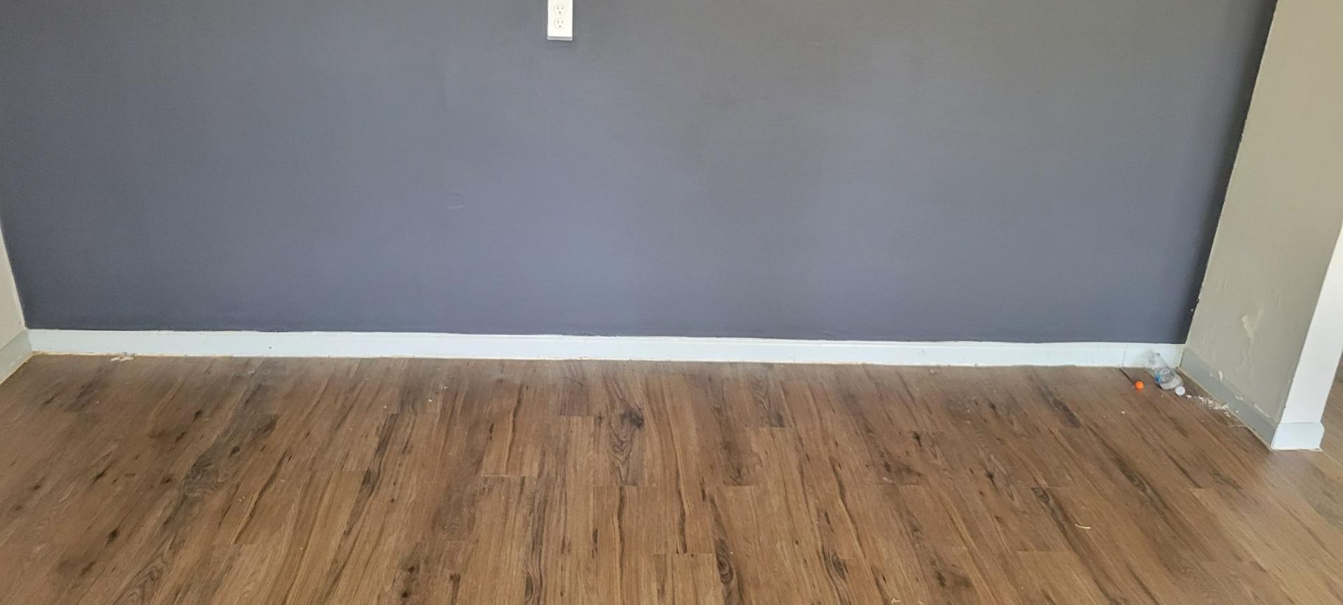 Room with wood floor, gray wall, white baseboard and trim.