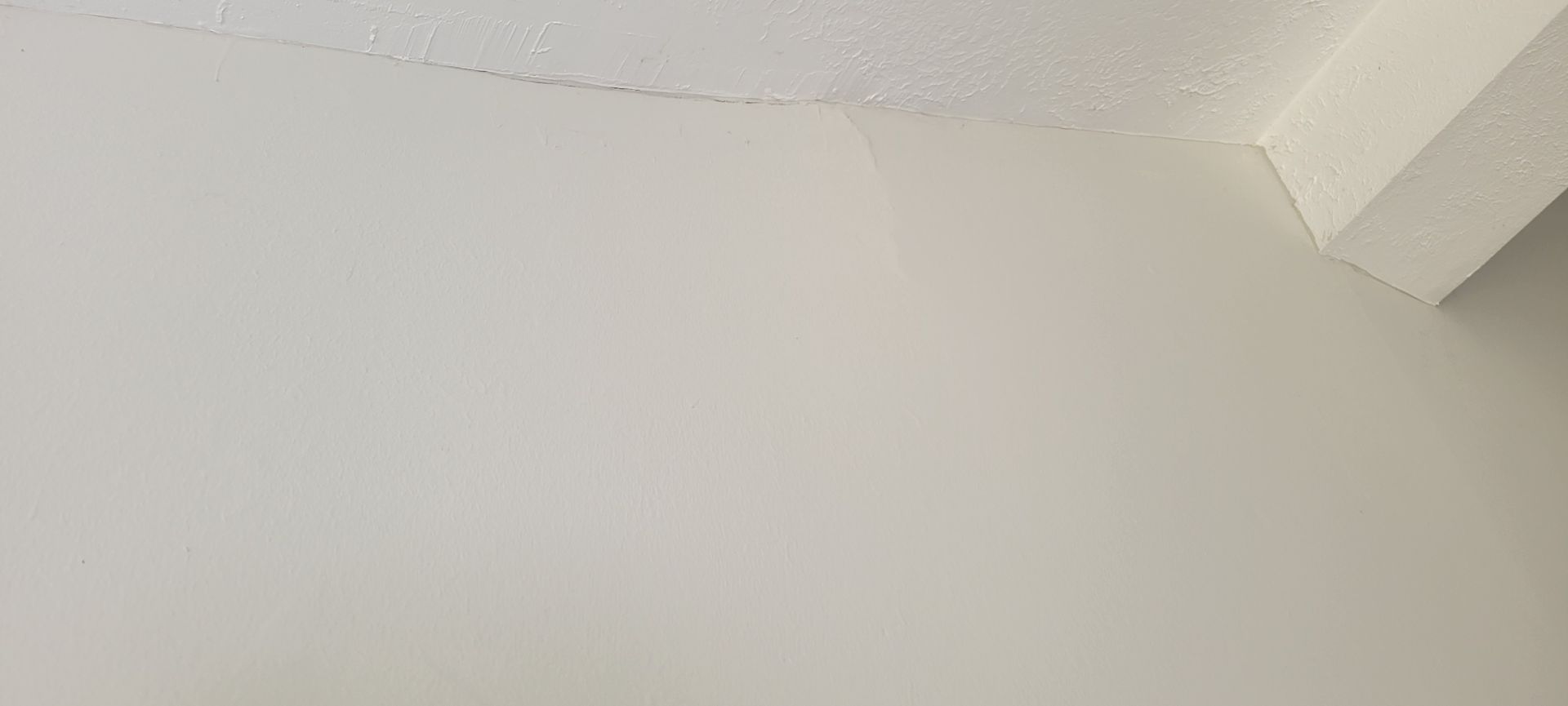 White wall and textured ceiling meeting at an angled corner.