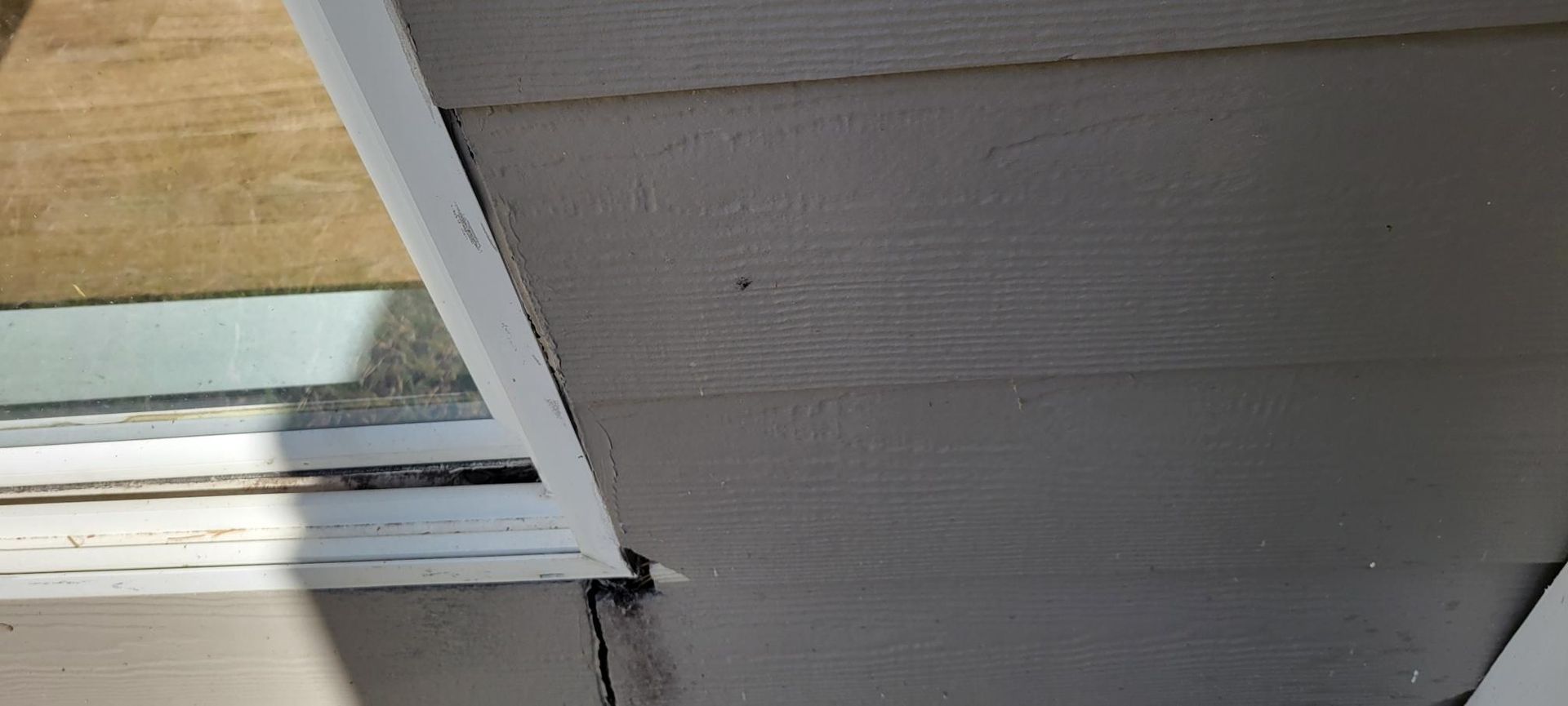 Close-up of a house exterior with gray siding and white trim.